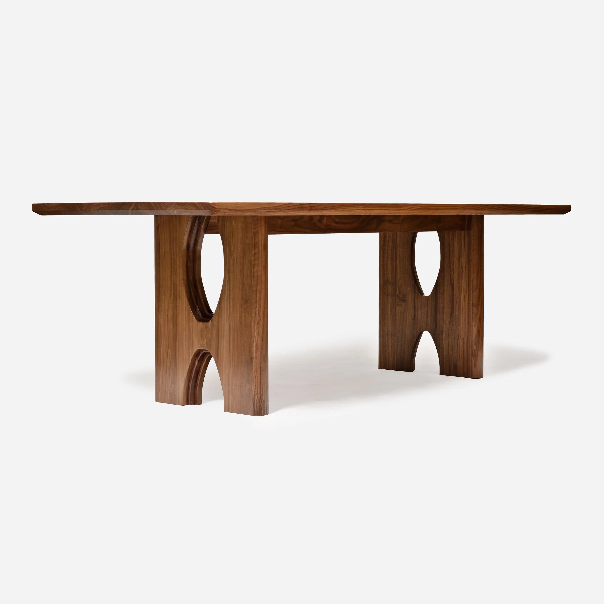 Profile view of heavy walnut dining table legs featuring mid-century modern inspired arch cutouts.