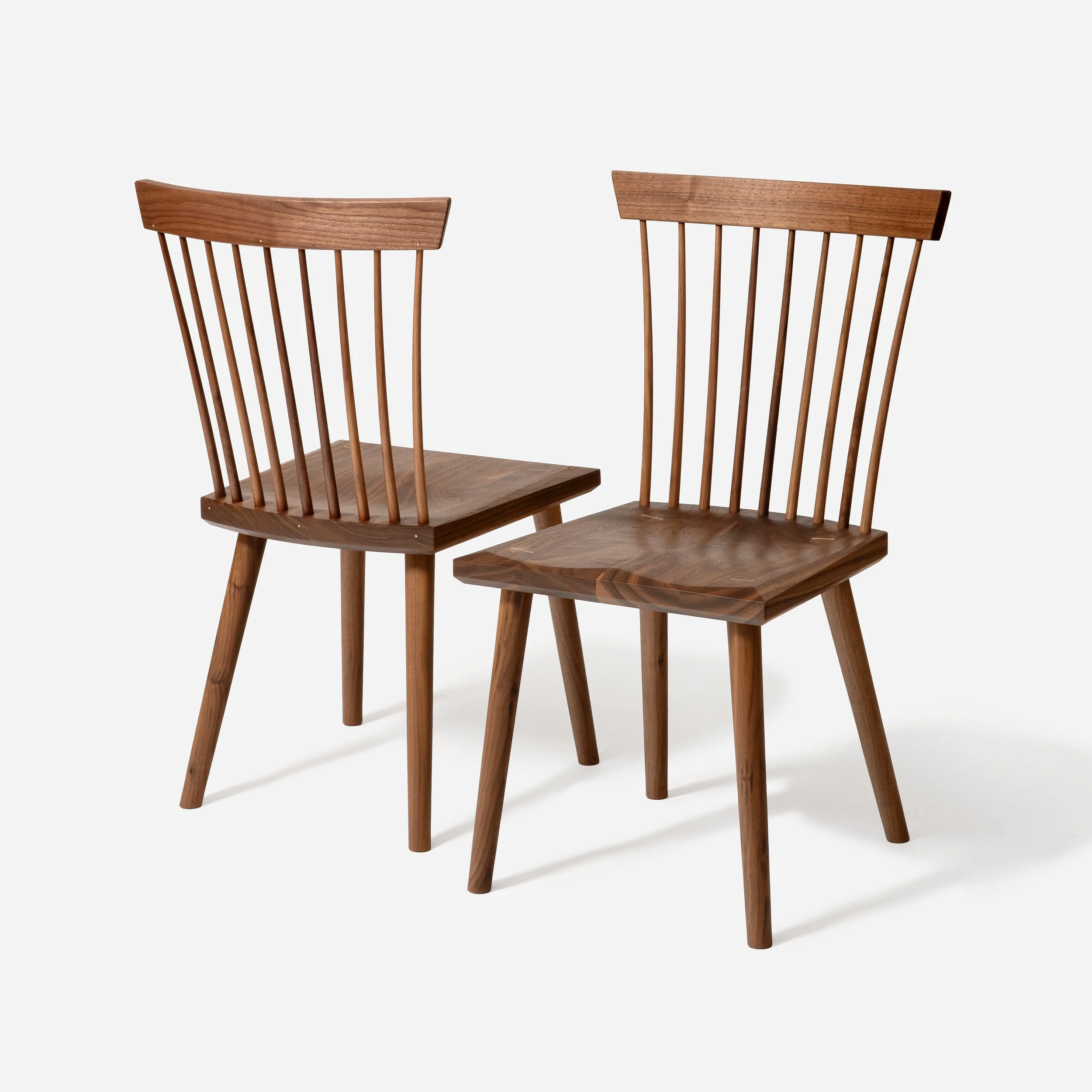 A pair of matching solid walnut spindle back chairs by Sustar Woodworks, highlighting the cohesive mid-century modern design.