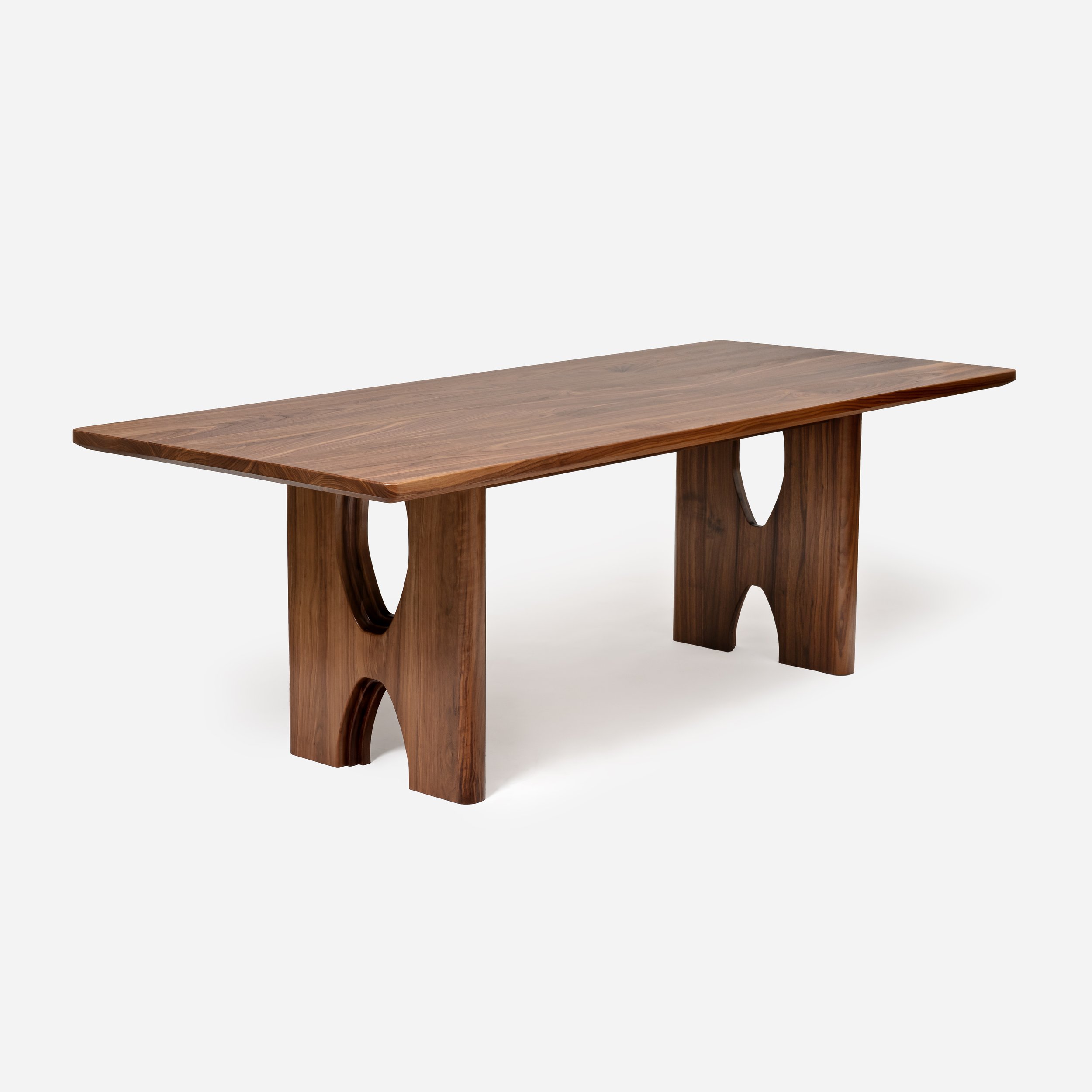 Sustar Woodworks bespoke solid walnut dining table with architectural arched trestle base and heavy timber top.