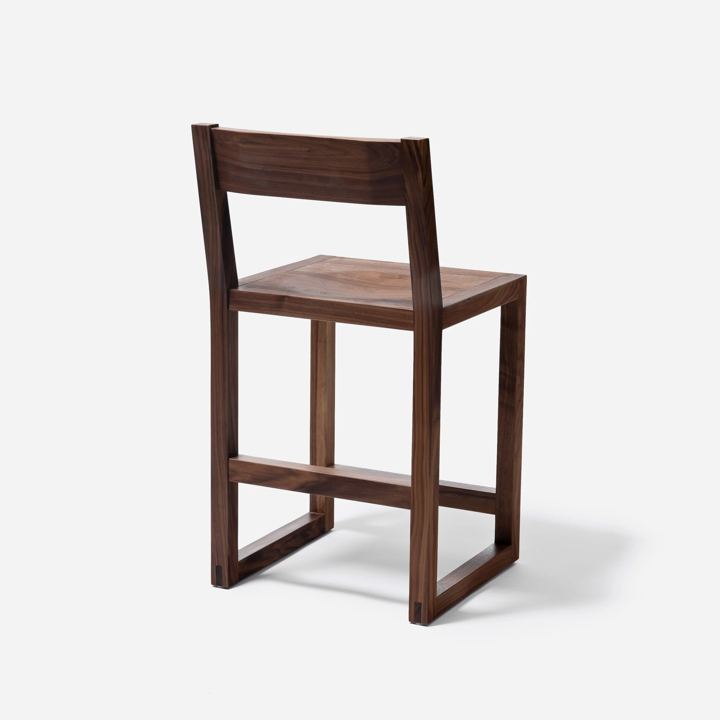 Handcrafted Tressa Bar Stool made from walnut wood with sculpted seat and backrest, traditional bridle joints, modern design, and expert craftsmanship, made in Milwaukee.