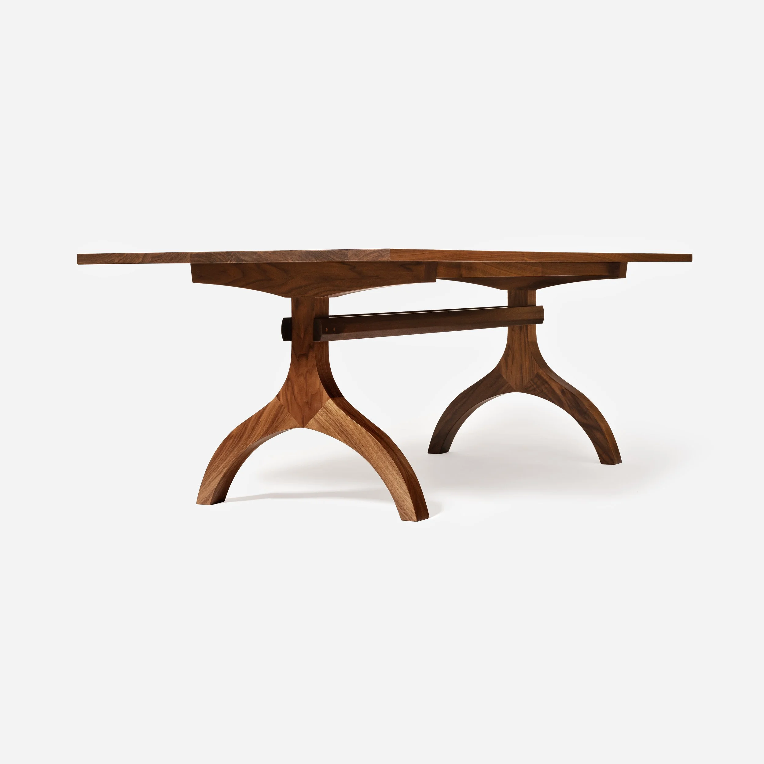 A low-angle profile studio shot of the solid walnut dining table