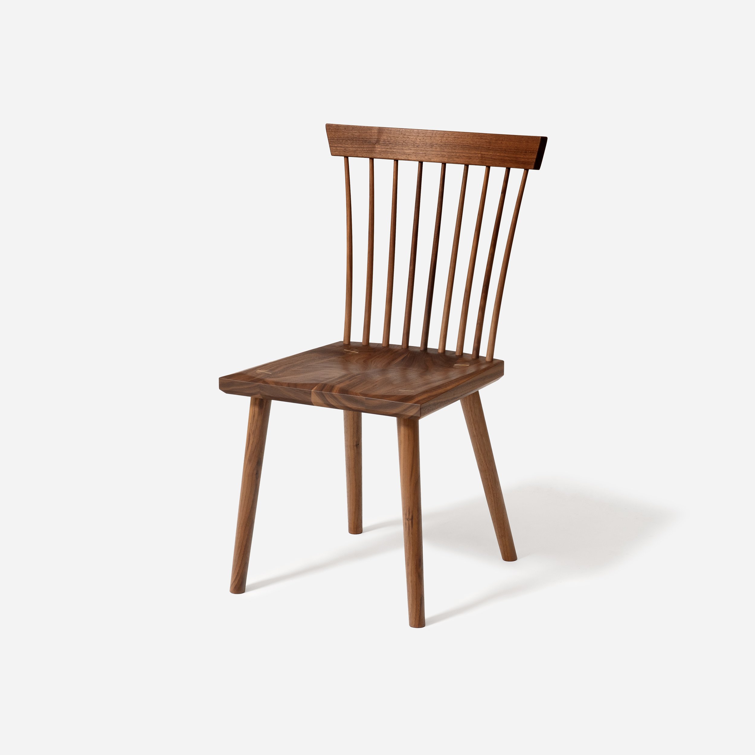 Sustar Woodworks hand-crafted solid walnut spindle back dining chair with sculpted seat and tapered legs.