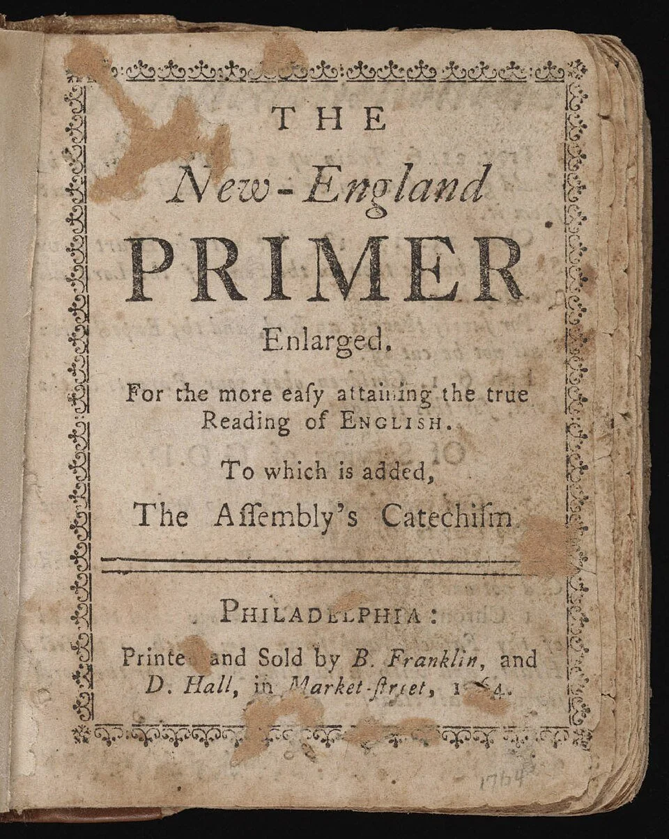 The title page of an old book titled 'The New-England Primer Enlarged,' published in Philadelphia by B. Franklin and D. Hall, with worn and stained paper, decorative border, and aged appearance.
