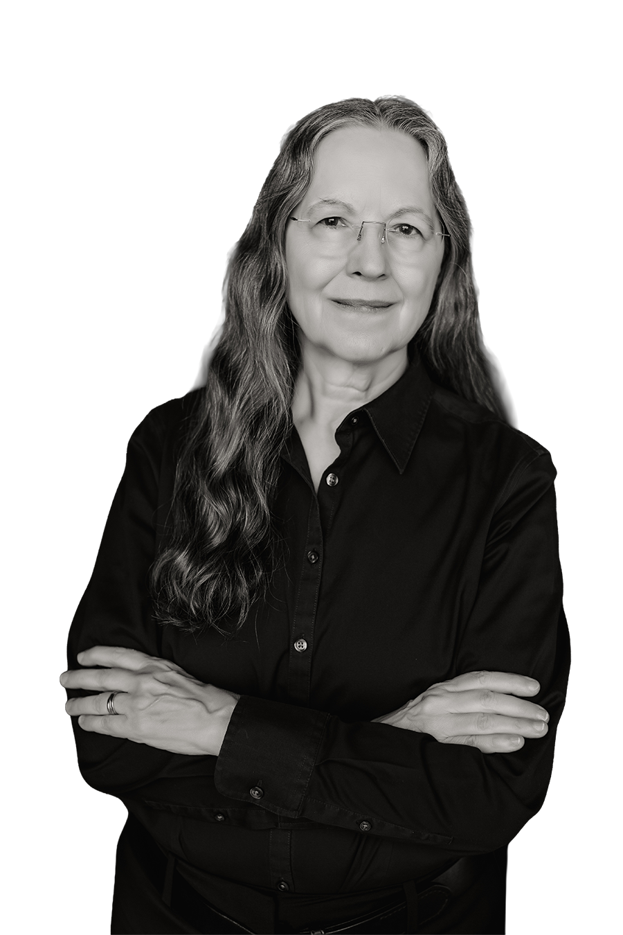 Black and white portrait of Jackie Blount with long wavy hair, glasses, wearing a black button-up shirt, arms crossed, smiling gently, against a dark background.