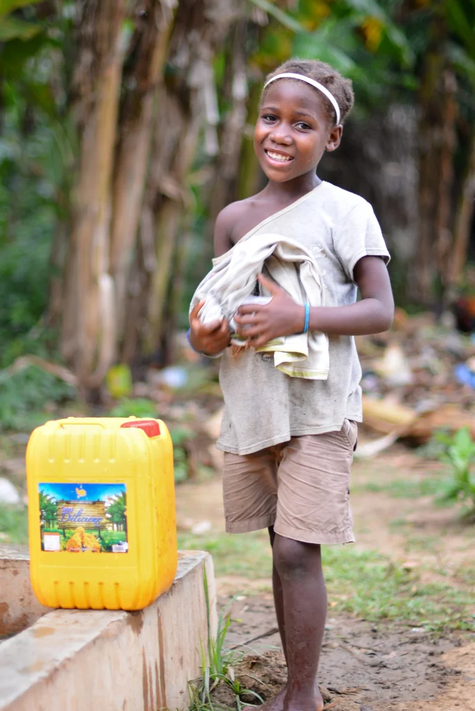Bringing well water home to her family wearing a smile.