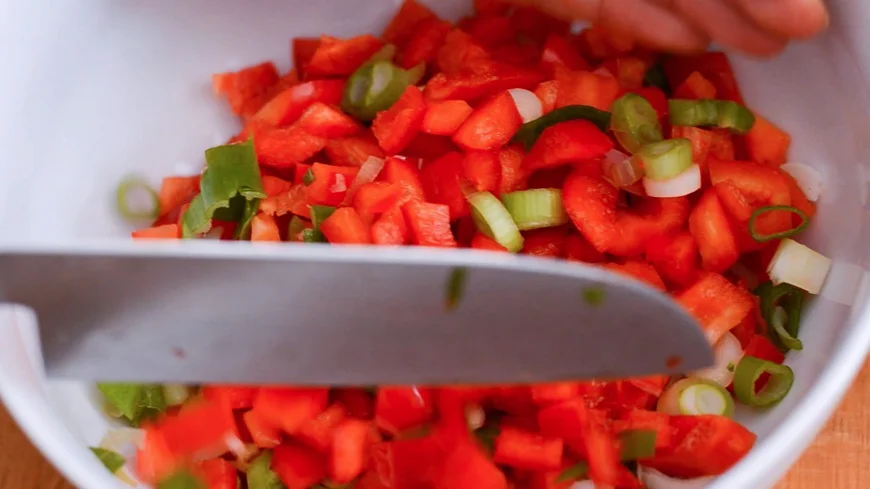 Frühlingszwiebeln und Paprika klein schneiden