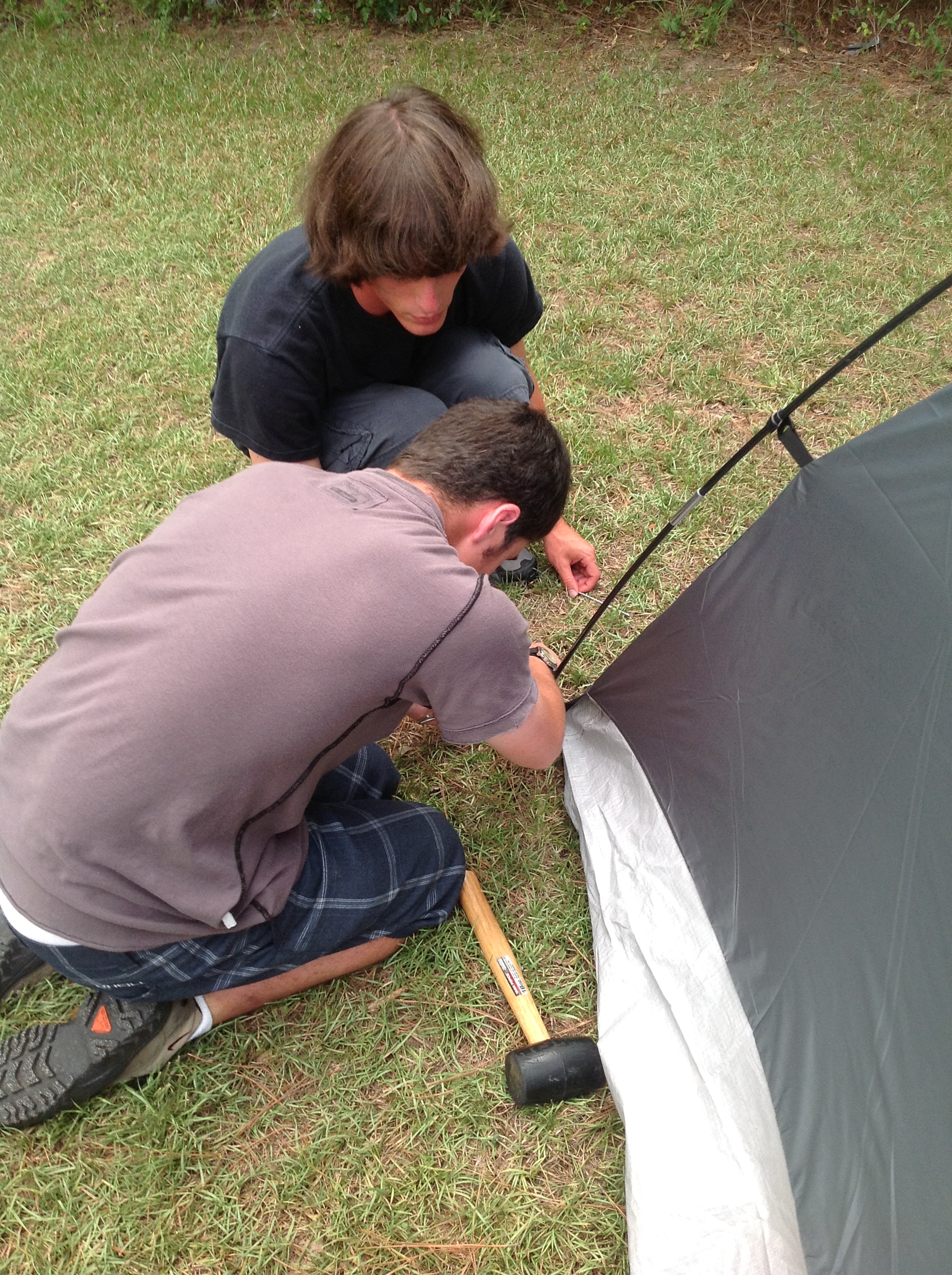Ben (counselor) and Matthew ensure that the tent is secure.