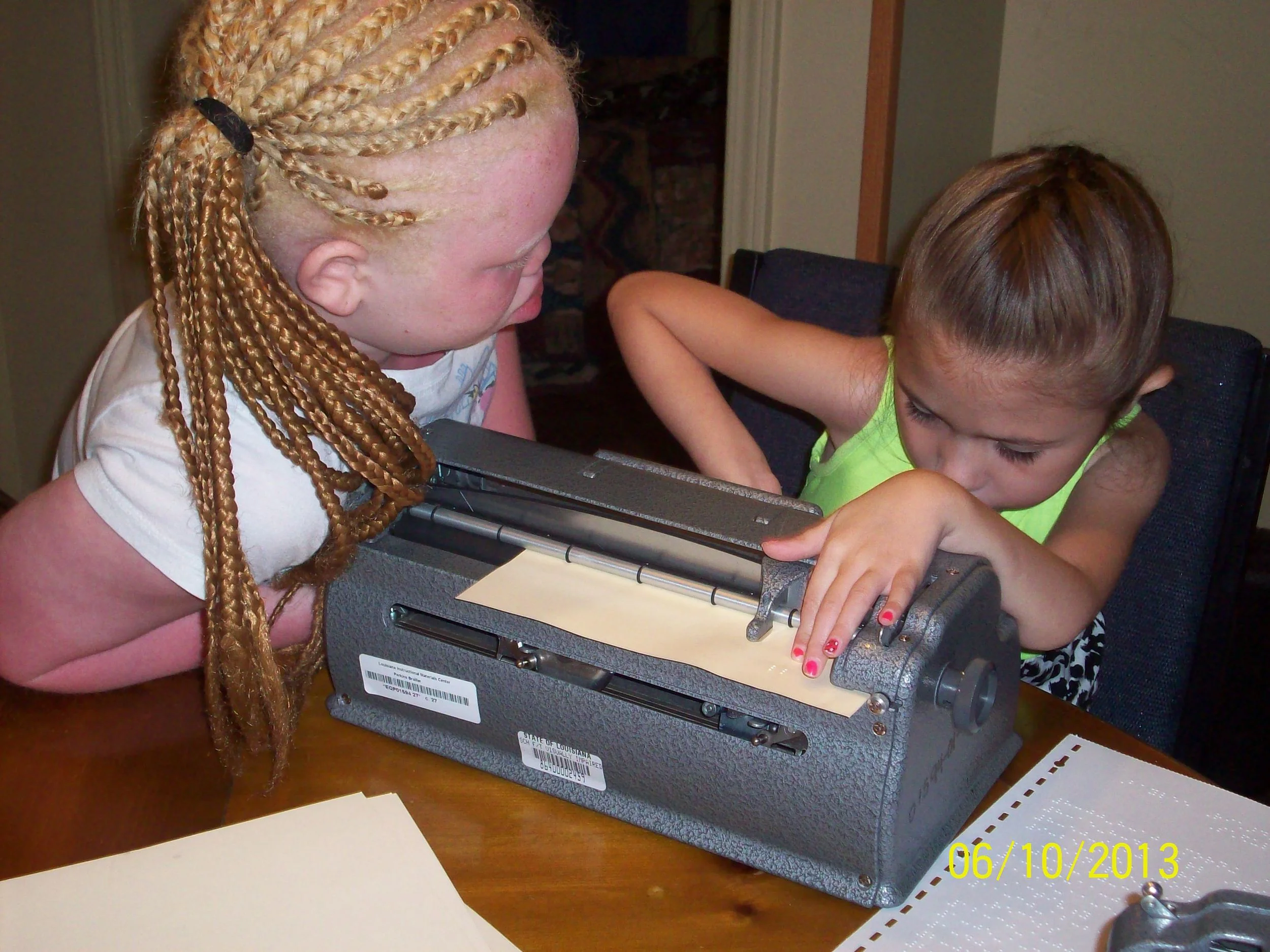 Rekendra helps Baylee write braille