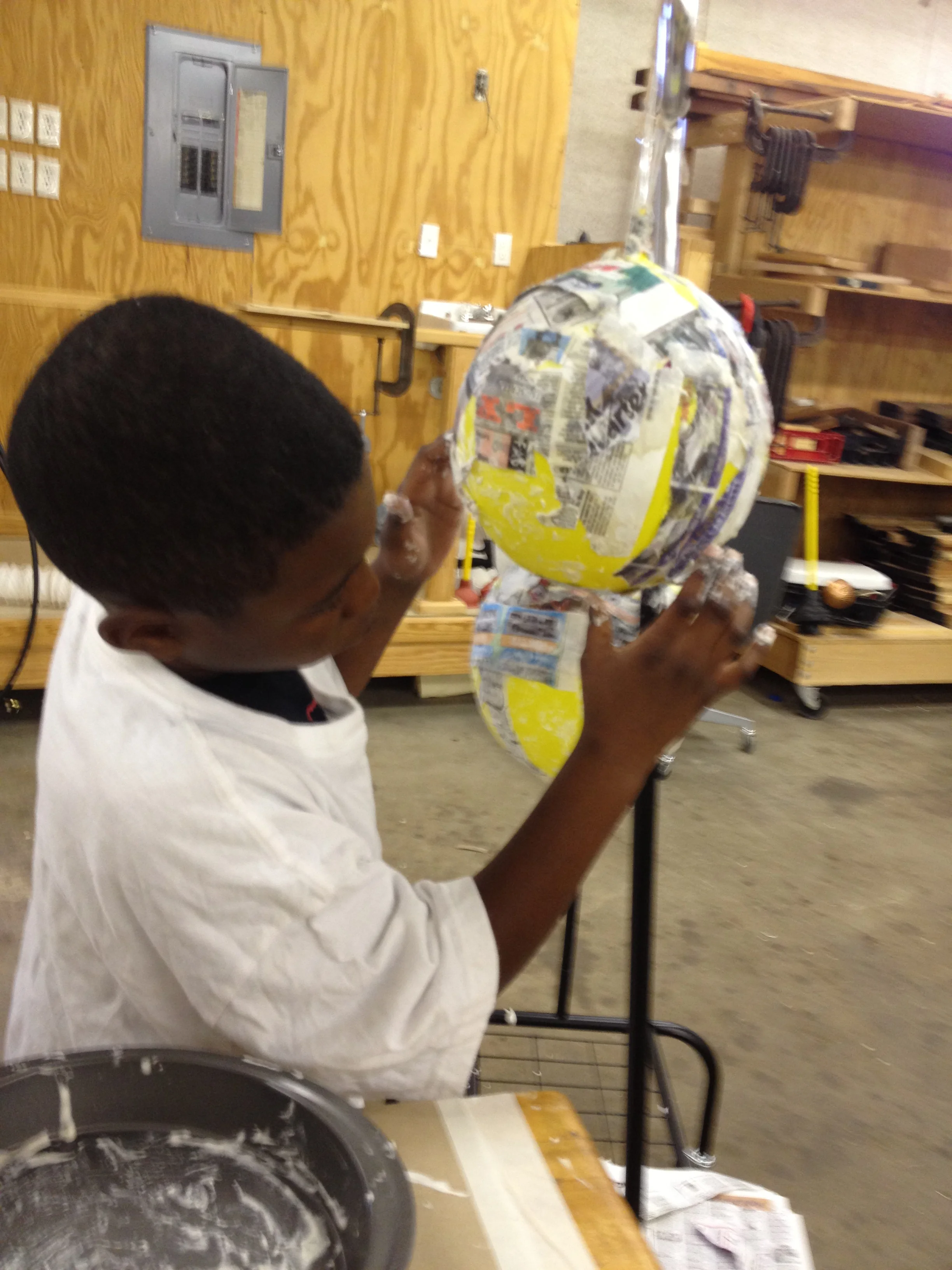 Braylon glues newspaper to a balloon in art class