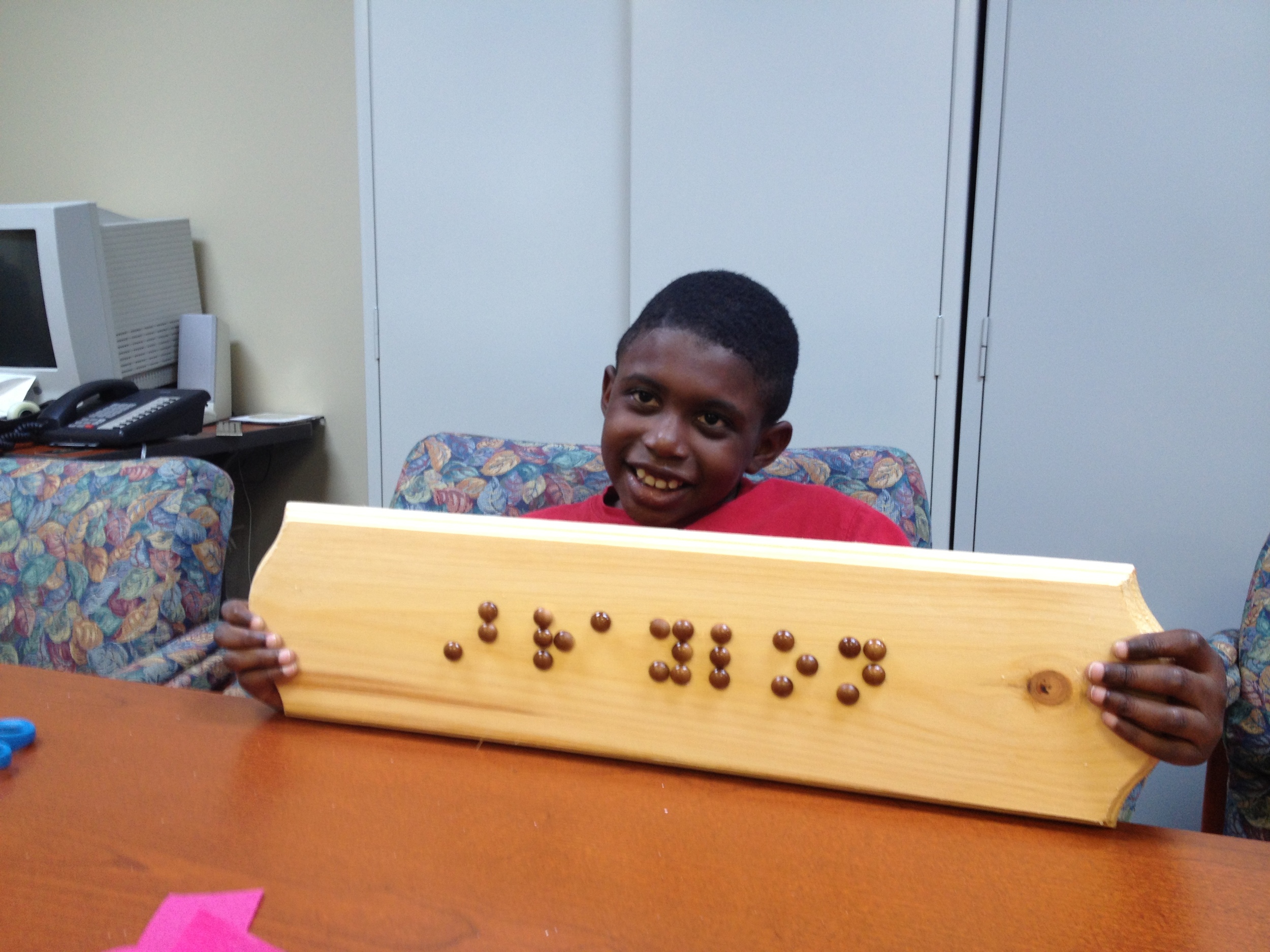 Braylon shows off his braille name plate made during the 2013 NFB BELL program
