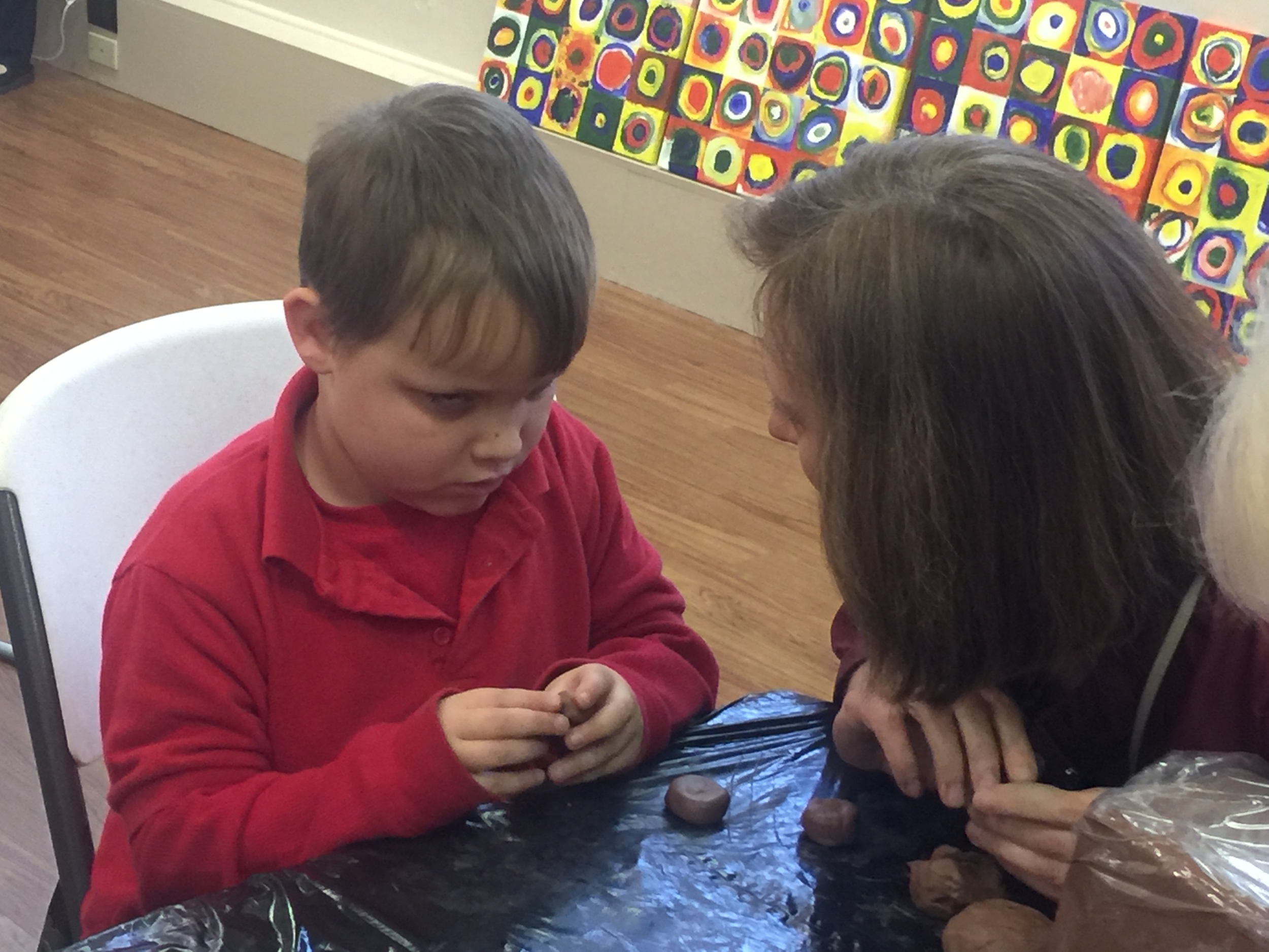 Isaiah molds his clay into small circles for his minature bike. His buddy, Allison--a LaTech TBS student--assist in the activity.