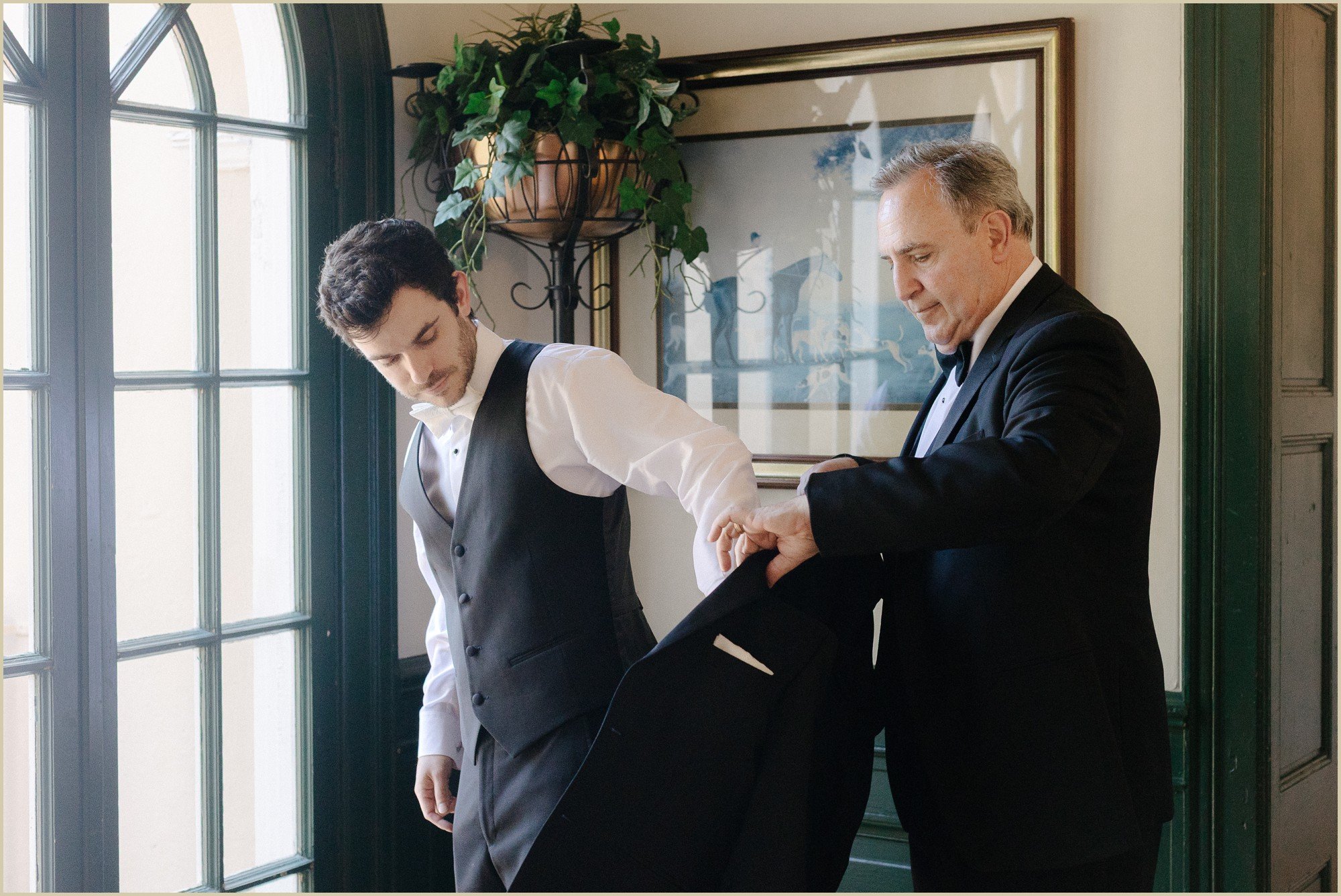 grooms father helping him into suit jacket