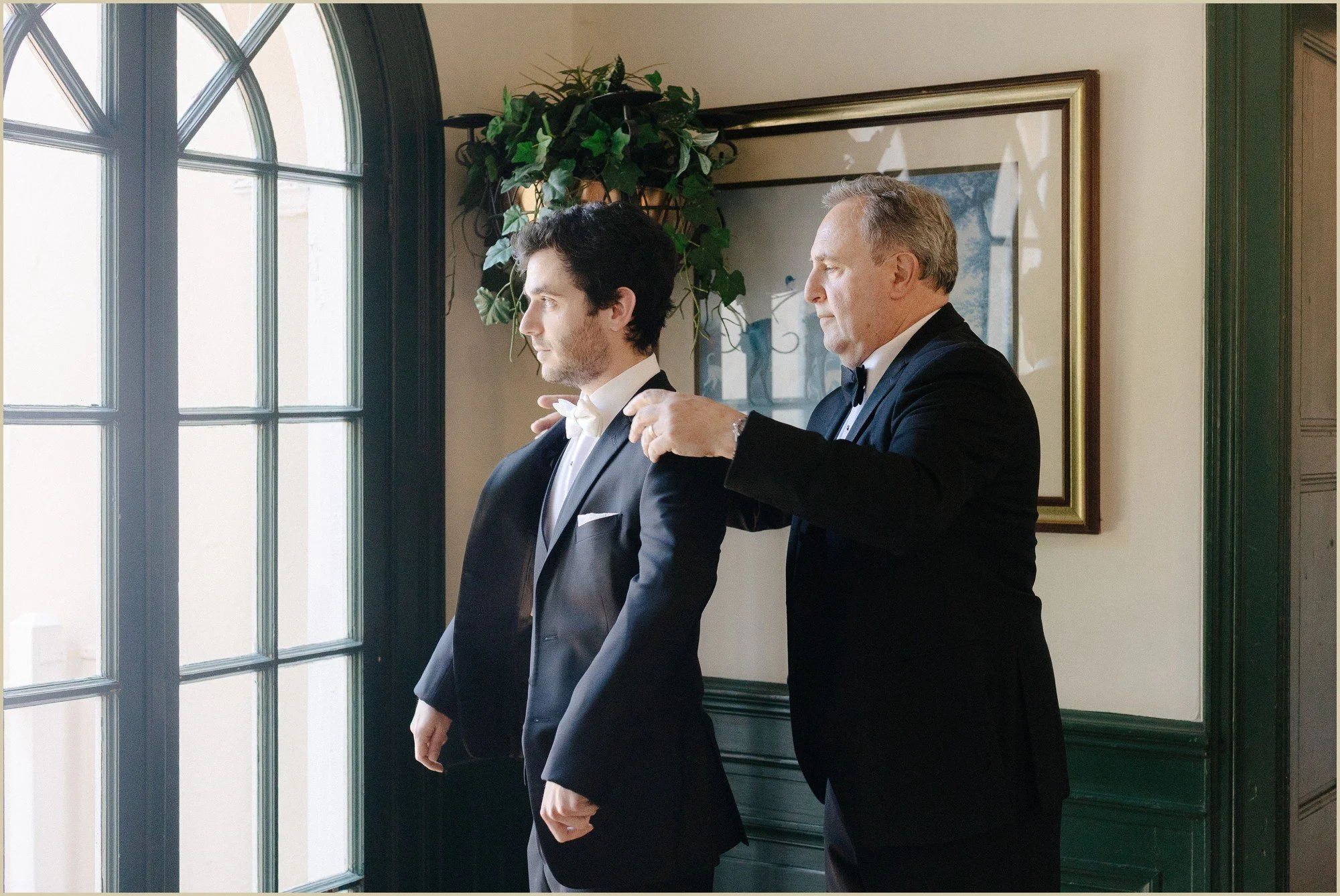 father of groom helping groom with jacket