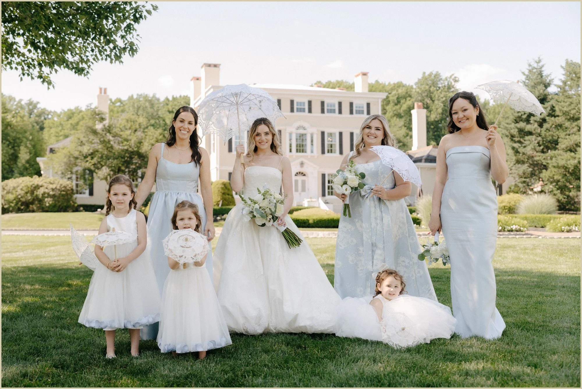 bridesmaids and flower girls with light blue dresses and parasols