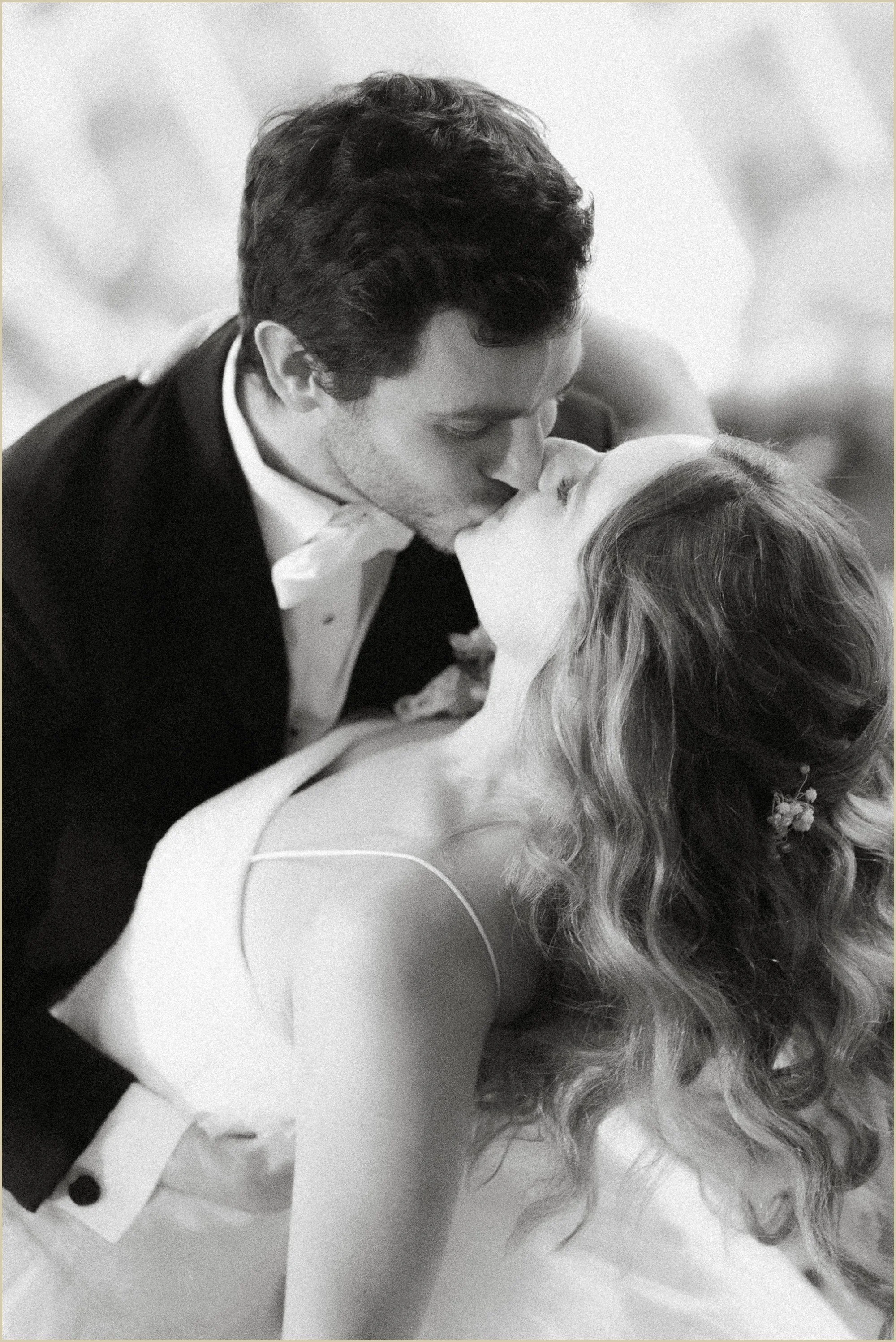 close up black and white photo of groom dipping bride and kissing her