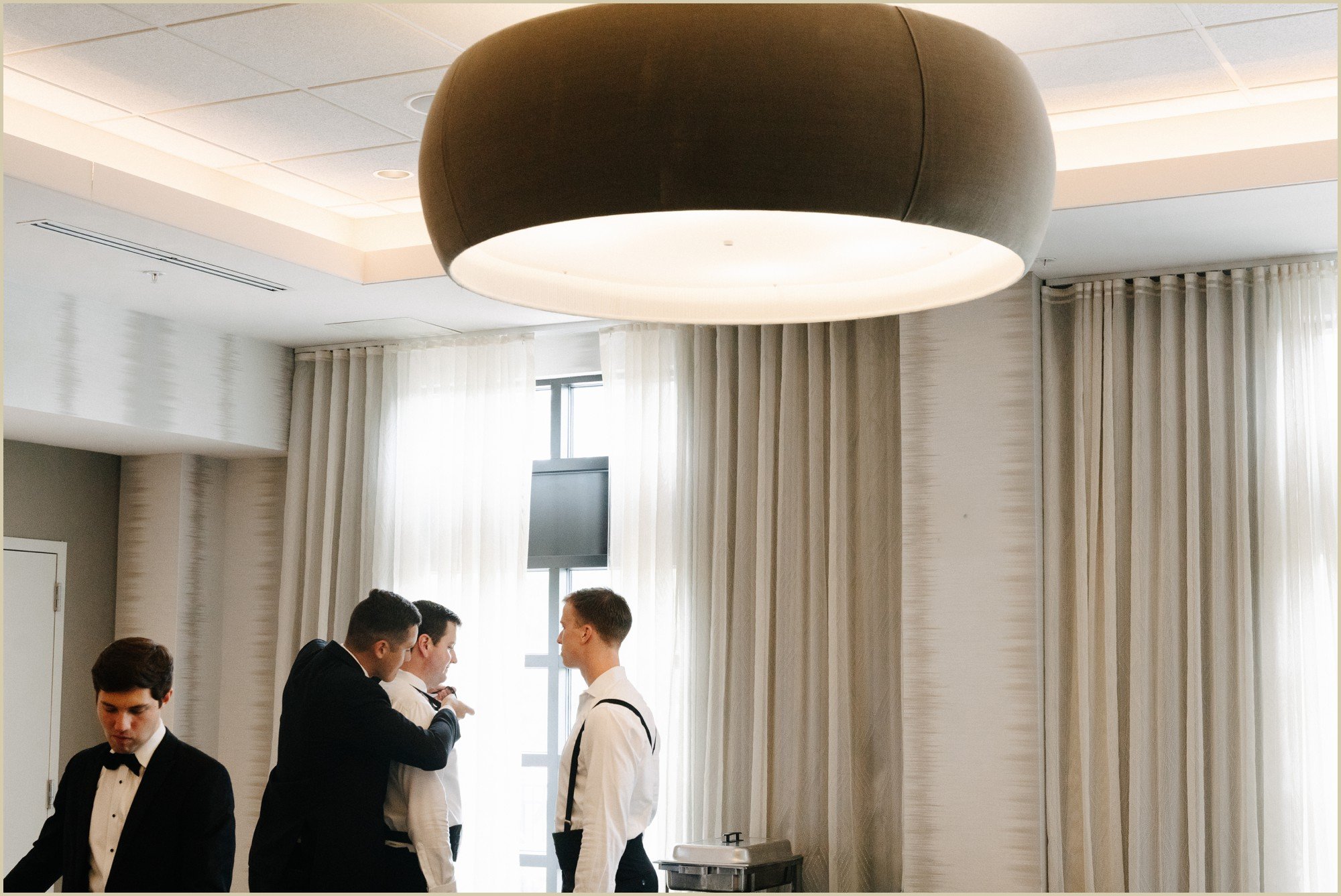 documentary style wedding photo of groomsmen helping groom get ready