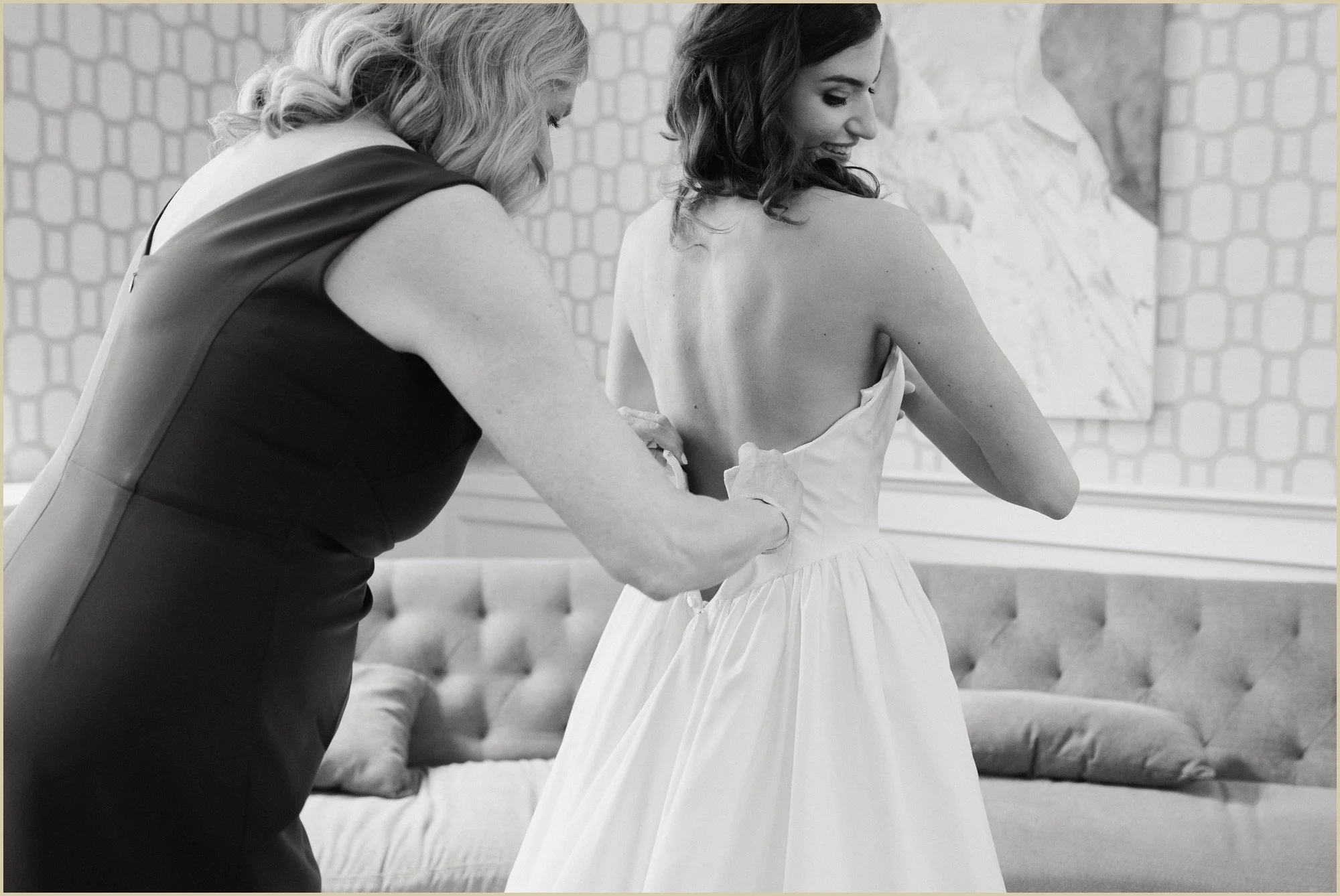 documentary style wedding photo of bride's dress being zipped up