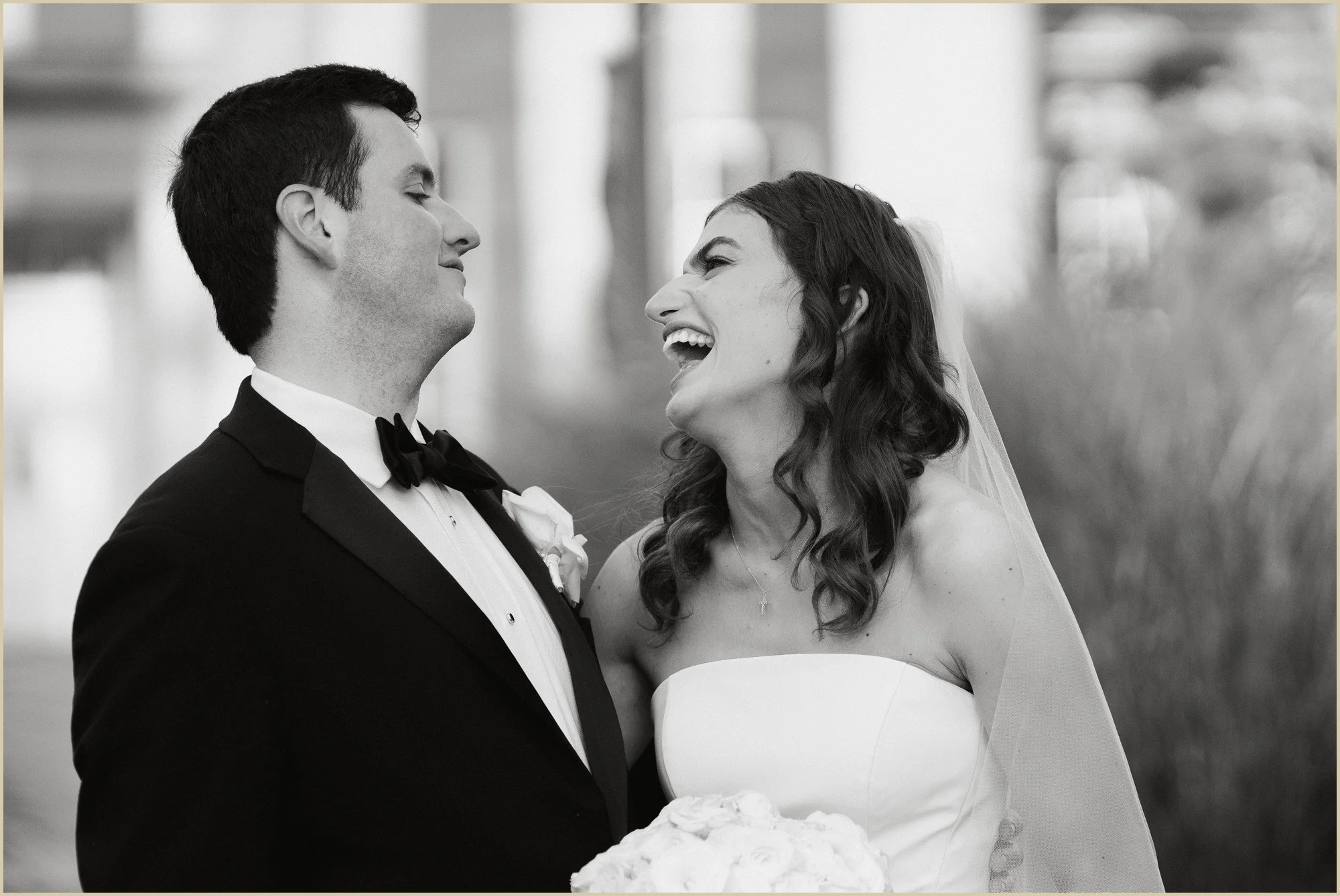 candid photo of bride and groom laughing and looking at each other