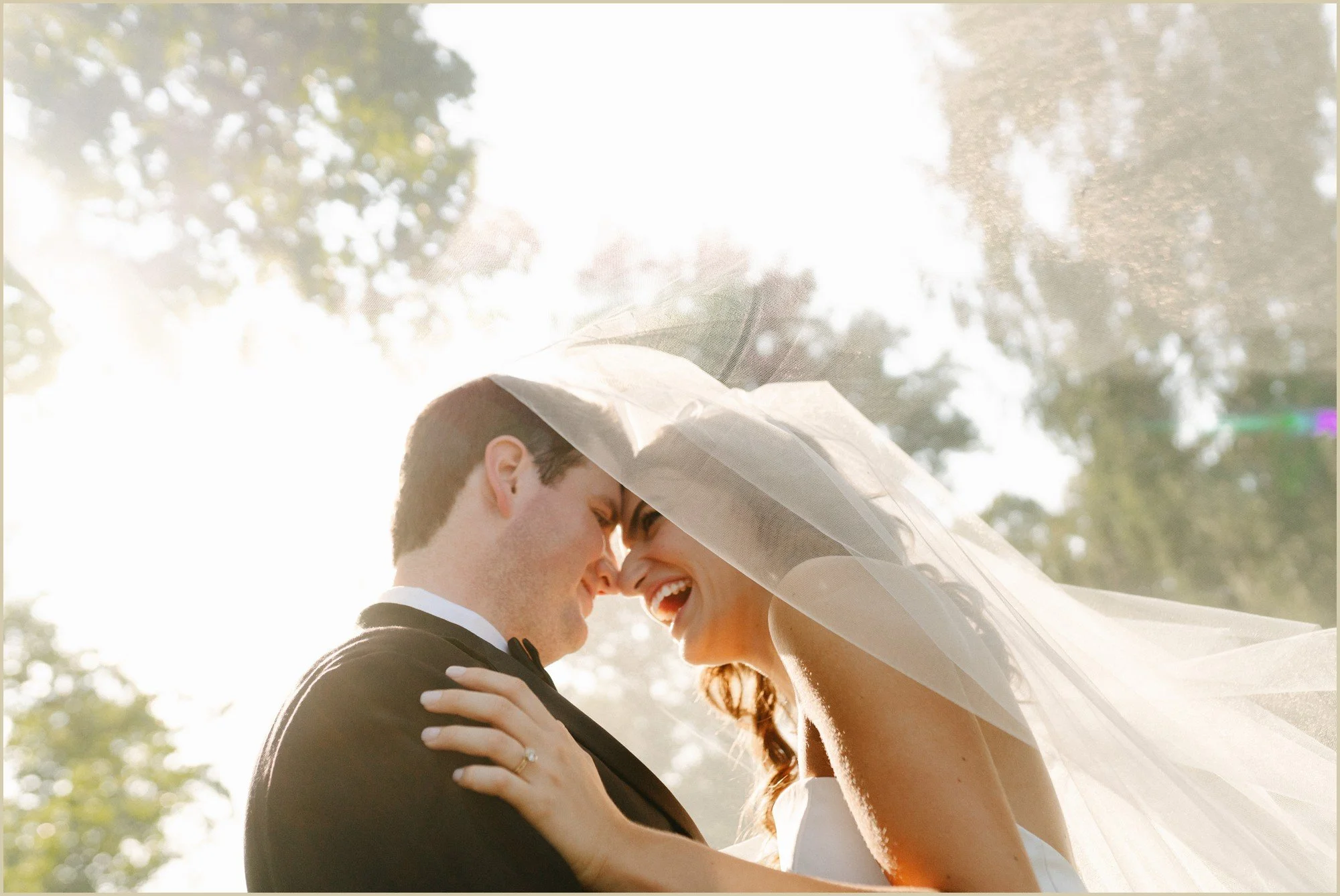 bride and groom laughing under the veil