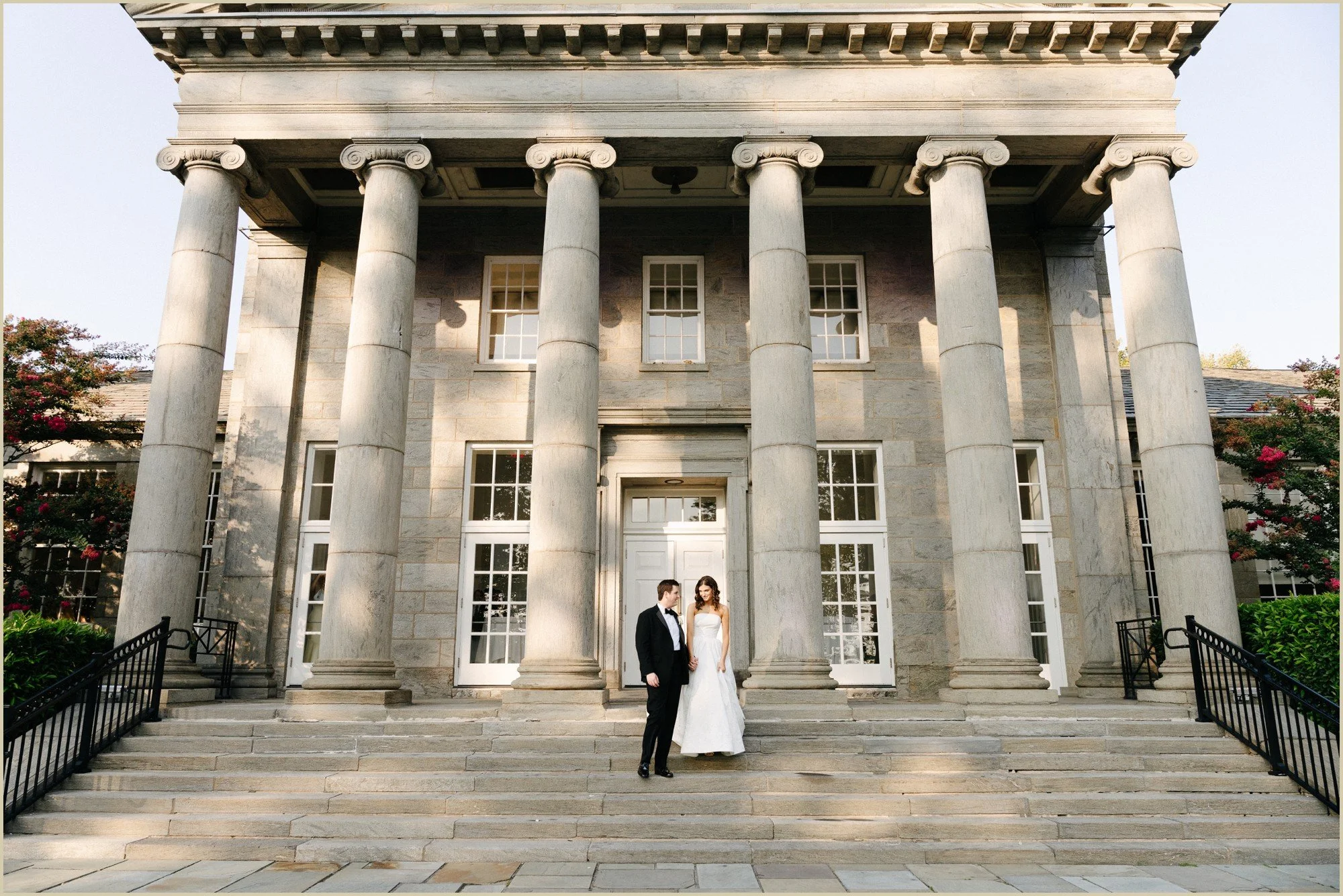wedding portraits on stone steps in front of large stone building with columns
