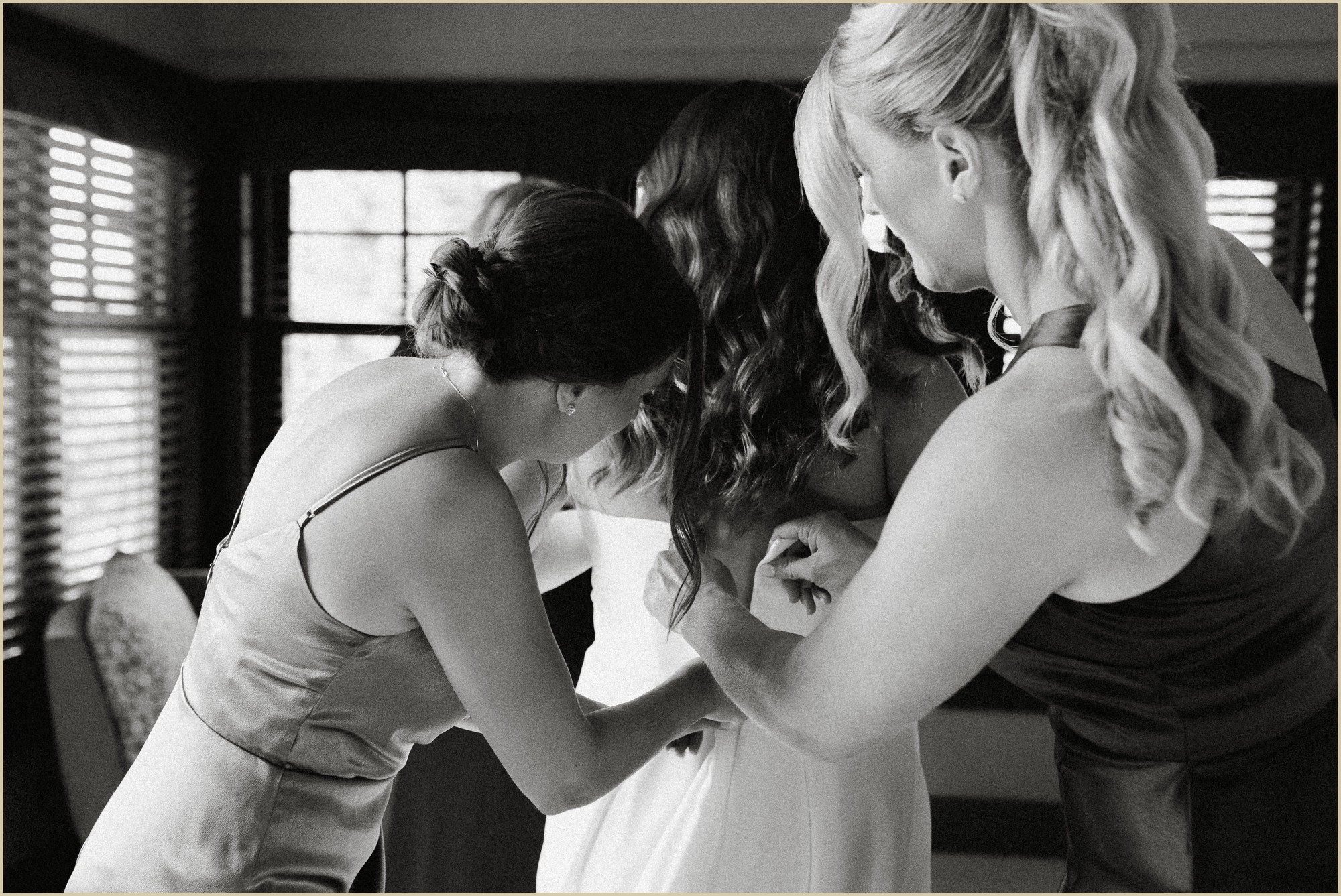 bridesmaids helping bride zip up dress