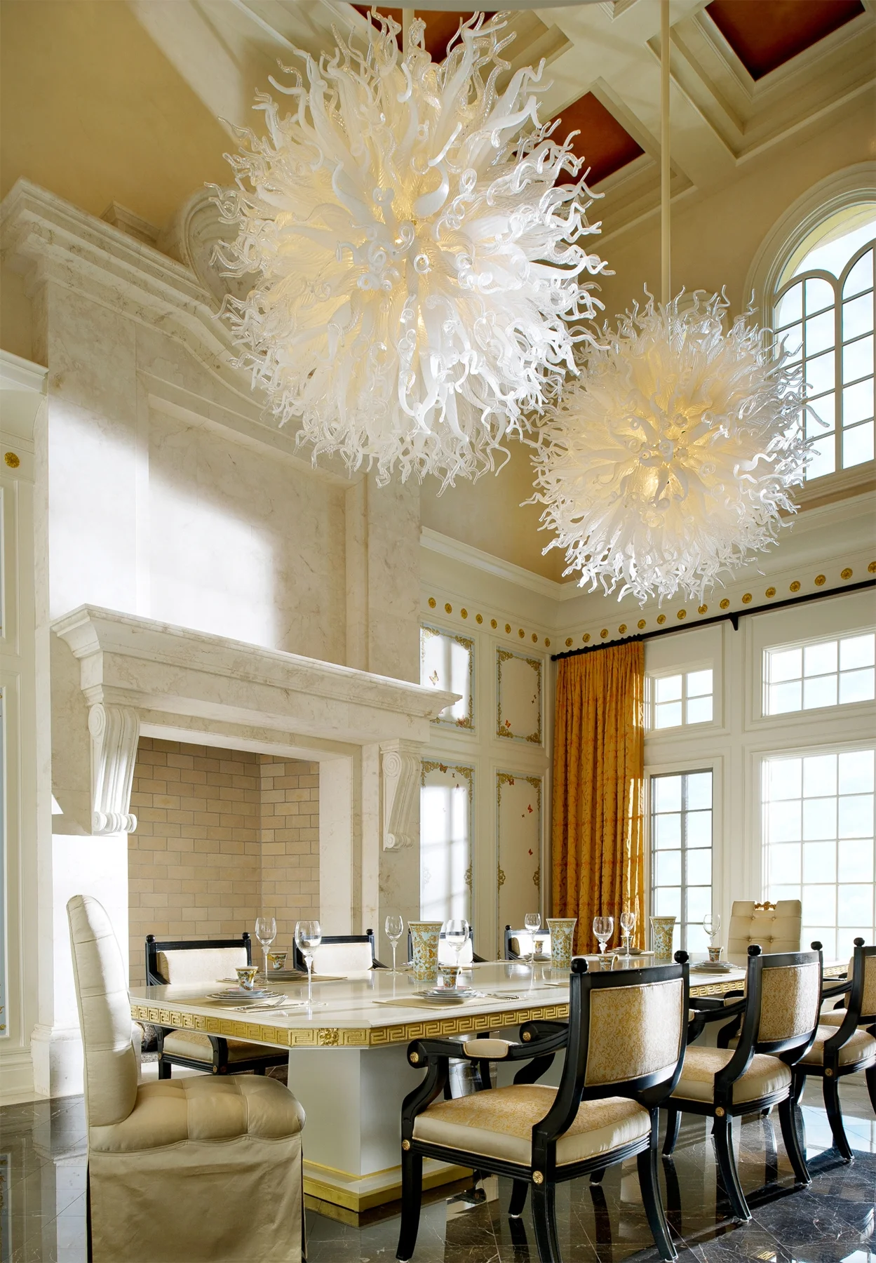 Statement making double chandeliers share this stunning dining room with a custom marble fireplace, gorgeous ceiling details and grand dining table built for a fabulous client in Naples, FL.