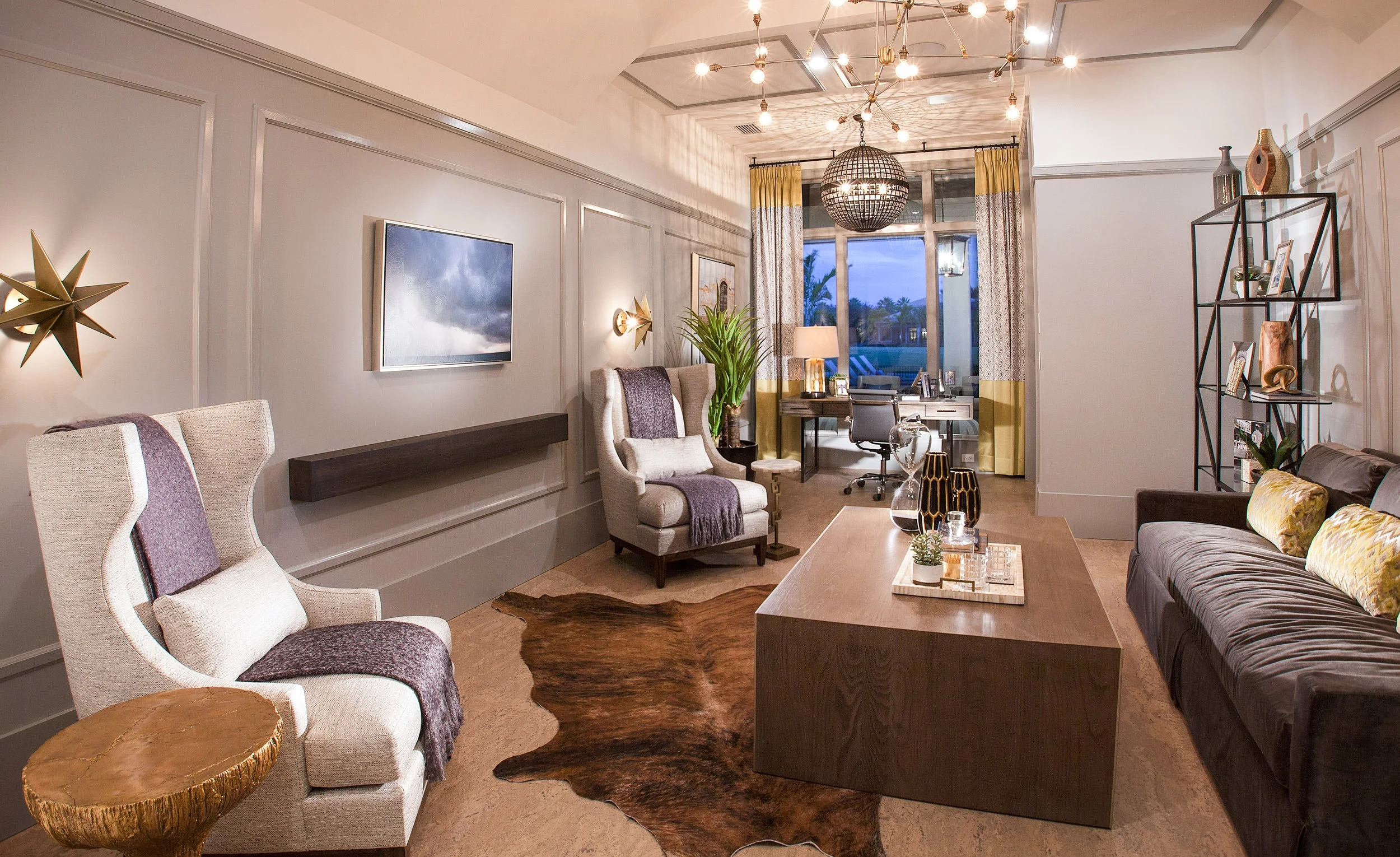 The modern light fixtures along with matching curved chairs, wood cocktail table, velvet sofa and cowhide area rug make for a stunning office design.