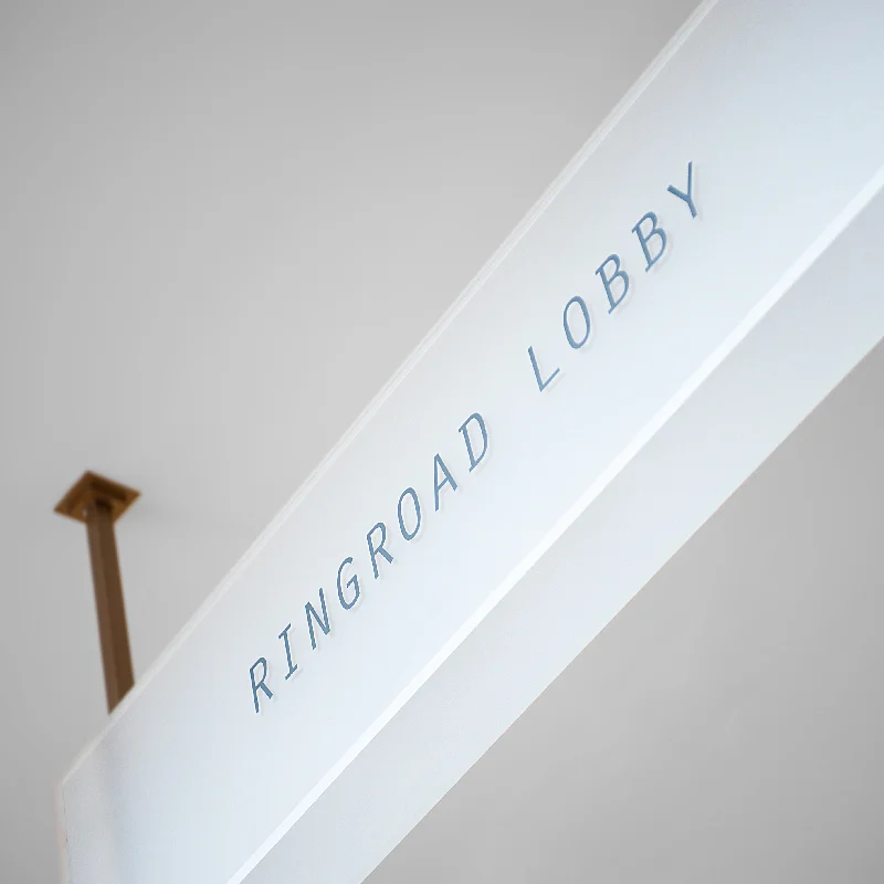 Overhead directional signage in frosted glass, with copper coloured metal frames. 