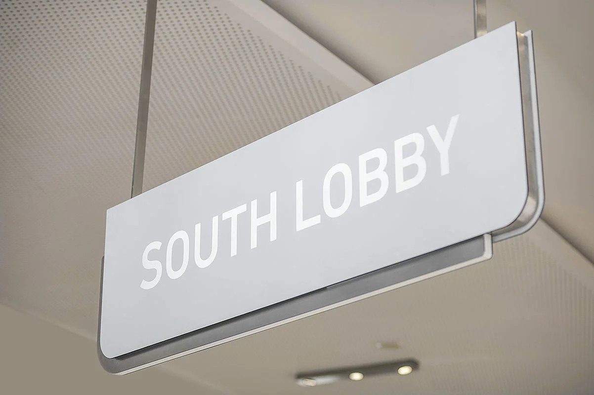 Overhead signage in matte white and stainless steel trim, with back lit graphics.