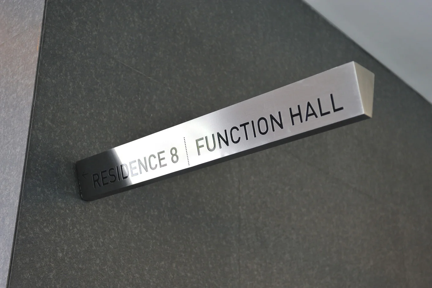 Overhead mounted directional signage in common corridors, in etched stainless steel.