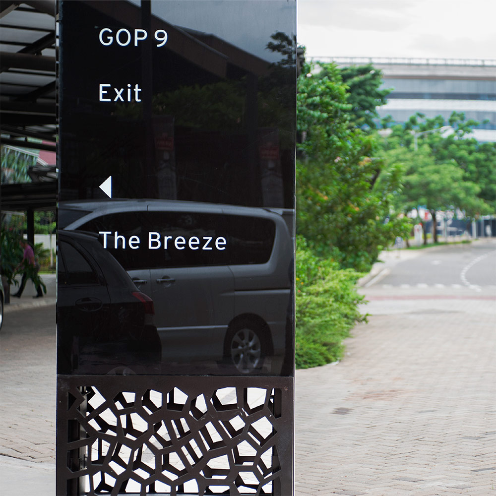 Vehicular directional signage in black backpainted glass, brushed stainless steel and white sticker content.