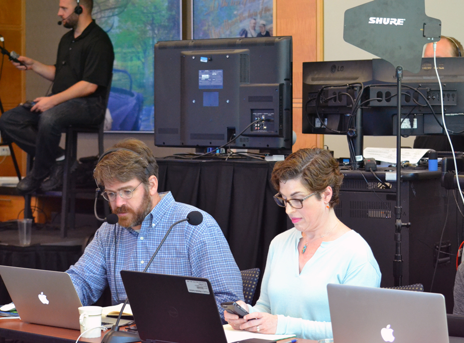 At a global town hall, on headset to coordinate with Production, at the laptop to drive speaking prompts, and seated with the internal comms lead to coordinate live Q&A.