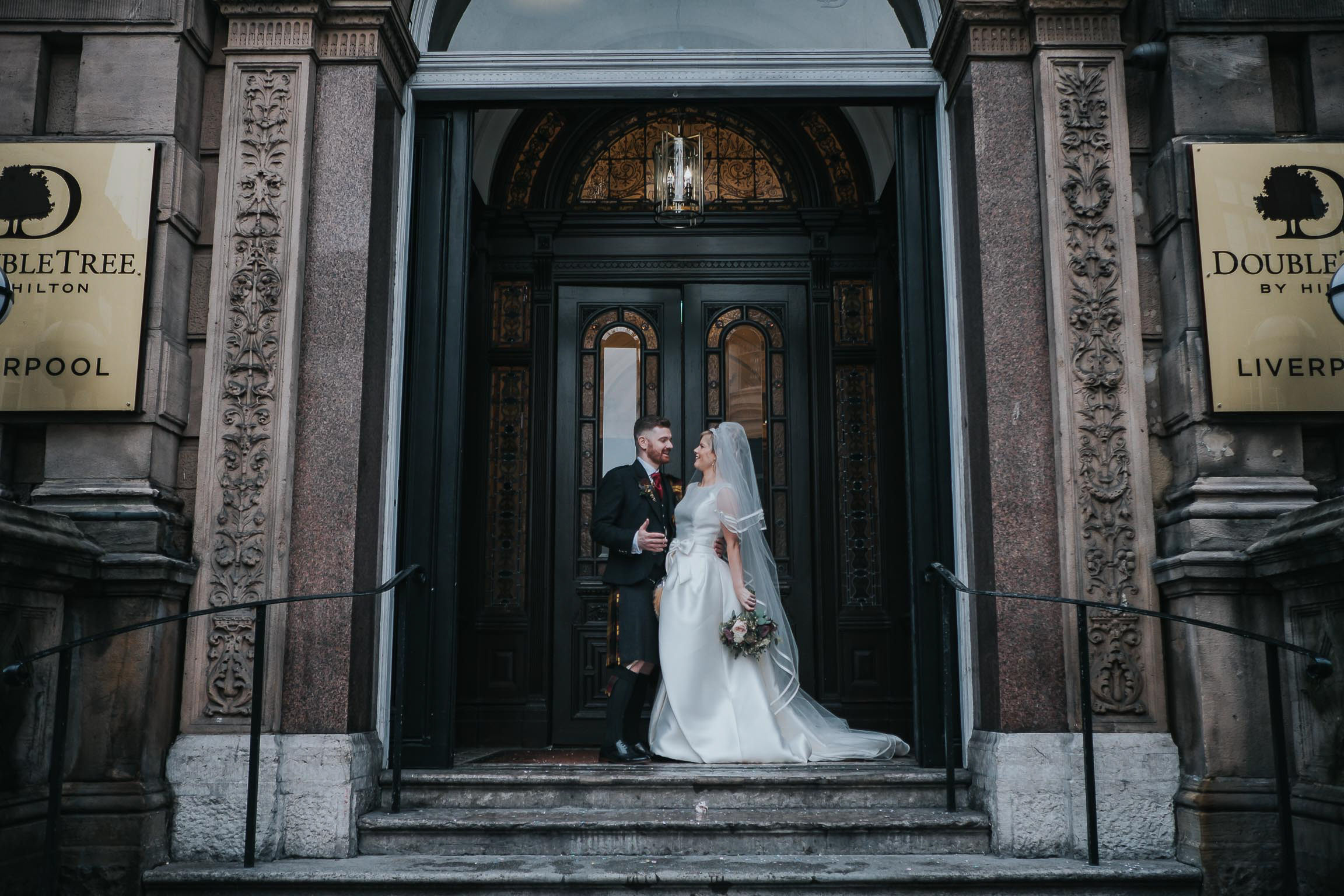 bride and groom on the steps at the front of the double tree by Hilton in Liverpool