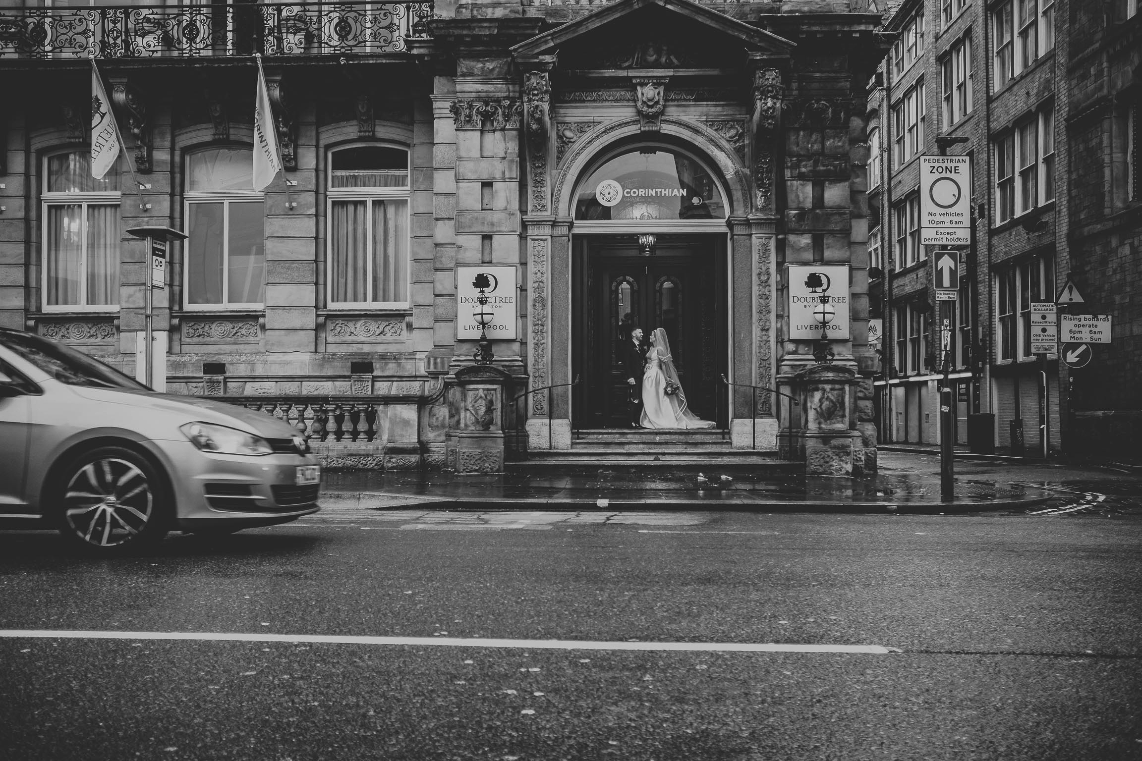 bride and groom outside the double tree in Liverpool with cars passing