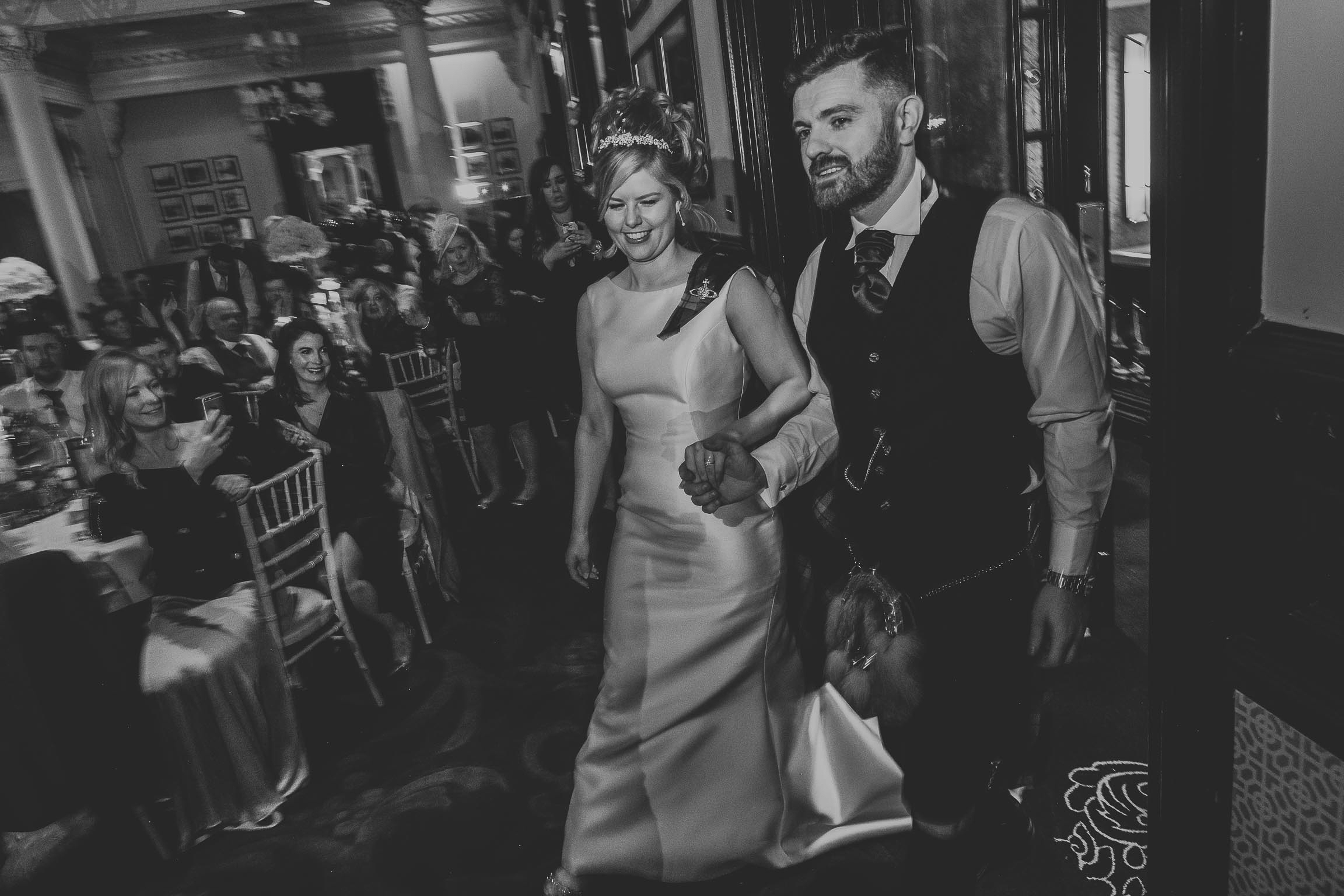 black and white image of a bride and groom being announced in to their wedding evening party