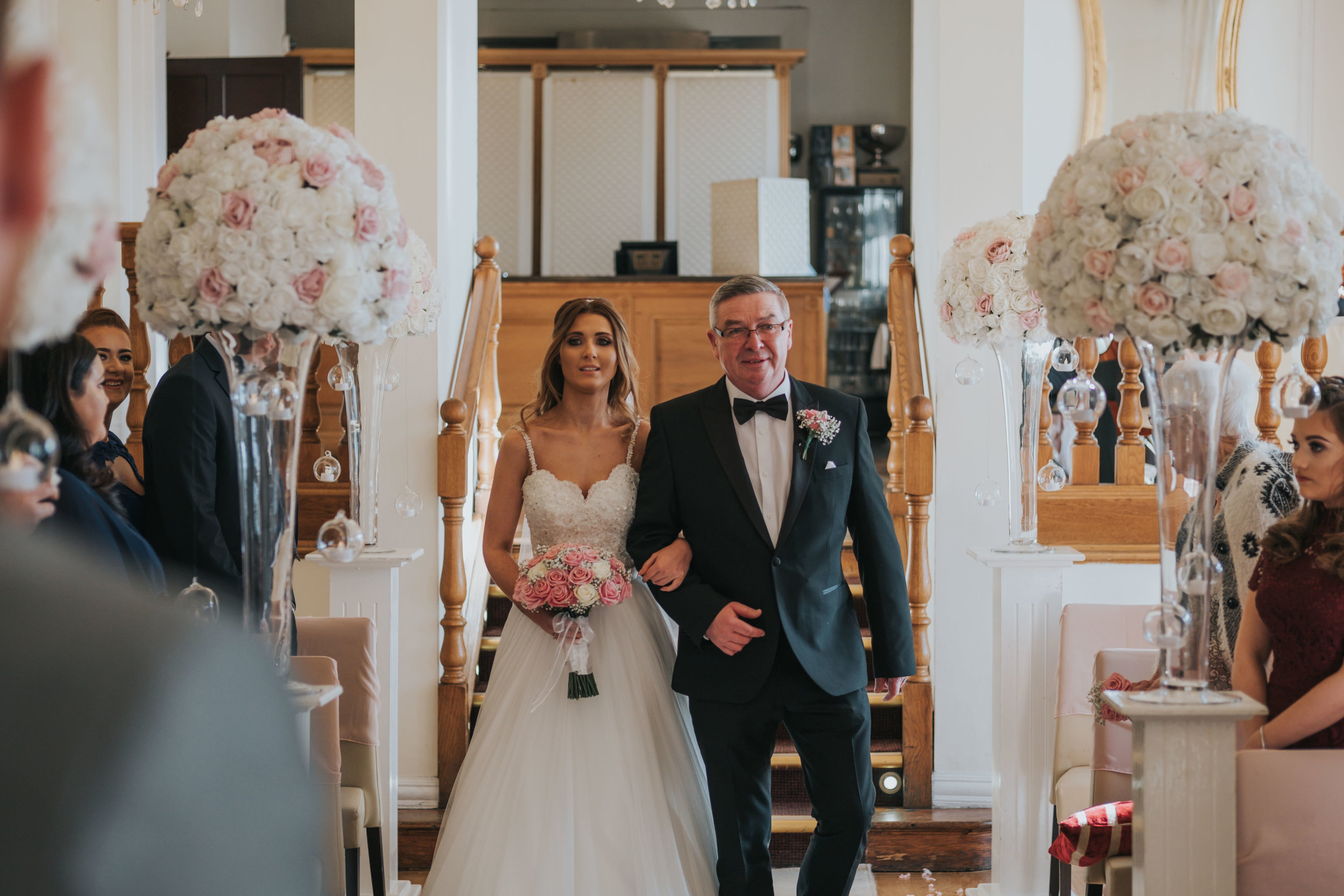 the bride and her father walking down the aisle on her wedding day at west tower exclusive wedding venue in ormskirk