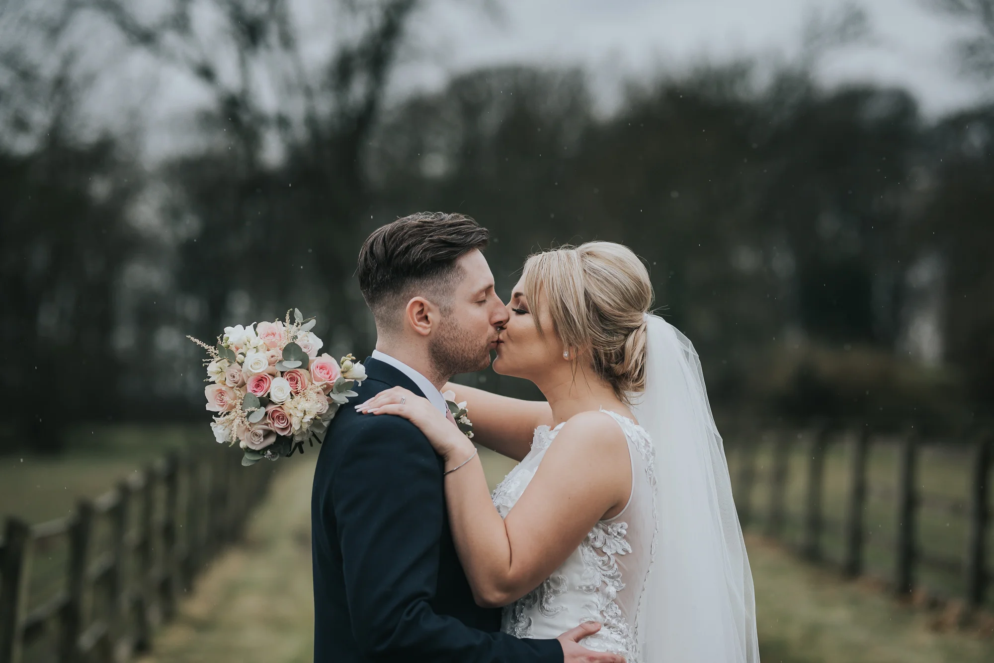 kissing in the rain on their wedding day  at The Villa in Wrea Green