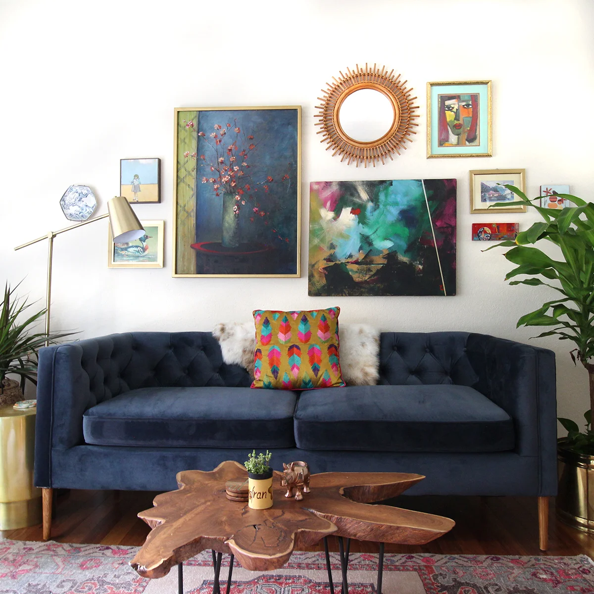  Living room featuring blue velvet sofa, live edge coffee table and colorful gallery wall by Kristin Laing Designs. 