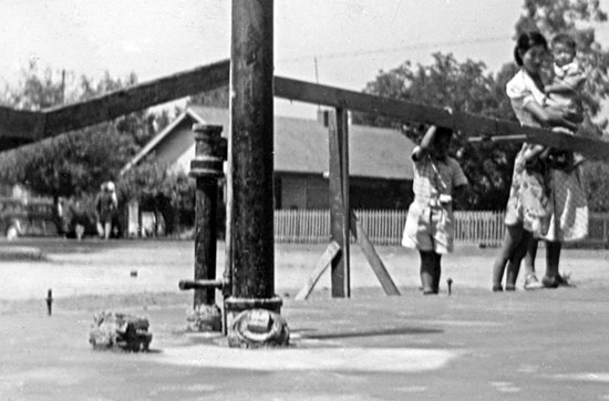 1940 ^ Picket fence at southwest corner Allen & King streets, with neighboring house to the south shown (in foreground: foundation for new grocery store, Mary Sakoguchi with her children) "This nice old black lady lived in a
