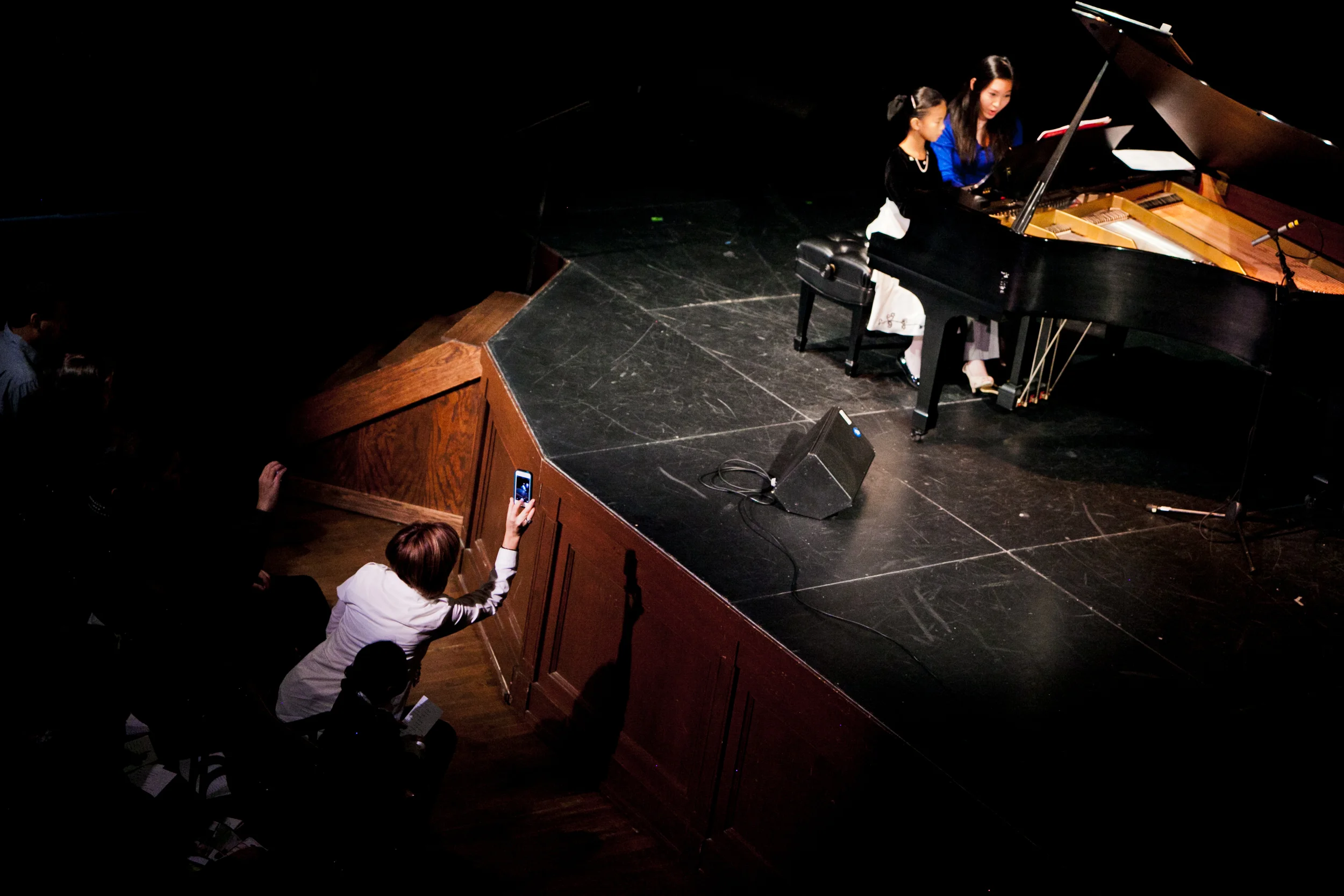 A proud mom photographs her daughter as she performs a duet with her teacher in our recital at McKinney Performing Arts Center.
