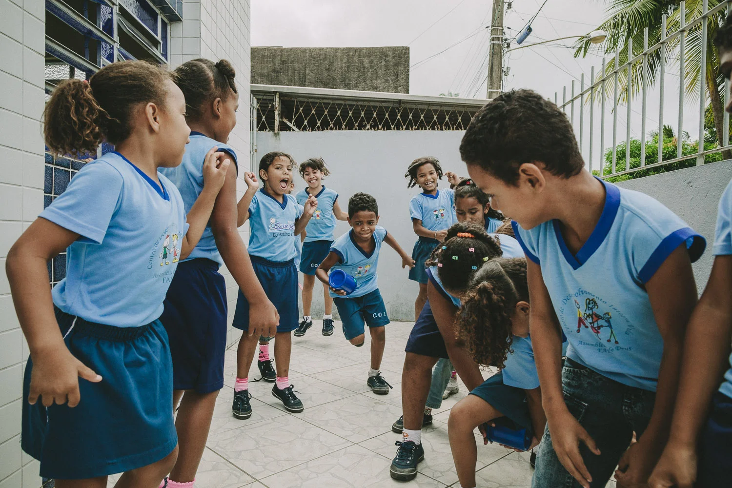 Emidio comes alive during action games and is very competitive. On this day, Emidio and his friends play a game where they must pass a cup between their legs to the person behind them and then run up to the front of the line. The goal is to have their group finish a whole cycle first.