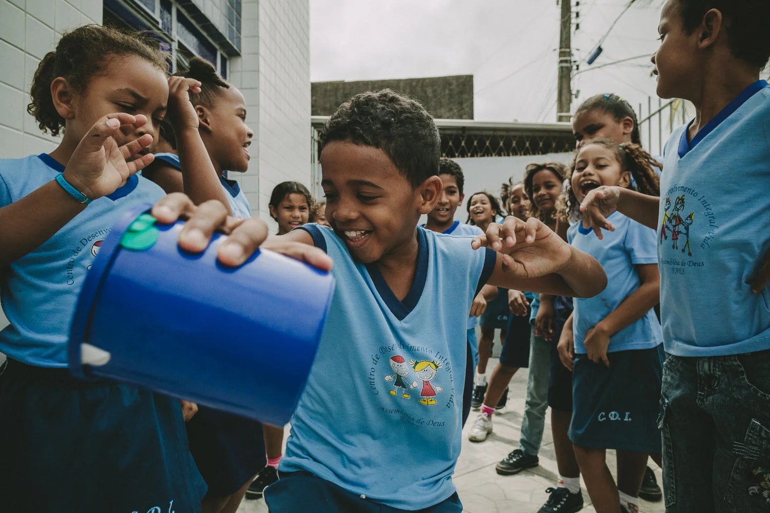 Emidio comes alive during action games and is very competitive. On this day, Emidio and his friends play a game where they must pass a cup between their legs to the person behind them and then run up to the front of the line. The goal is to have their group finish a whole cycle first.
