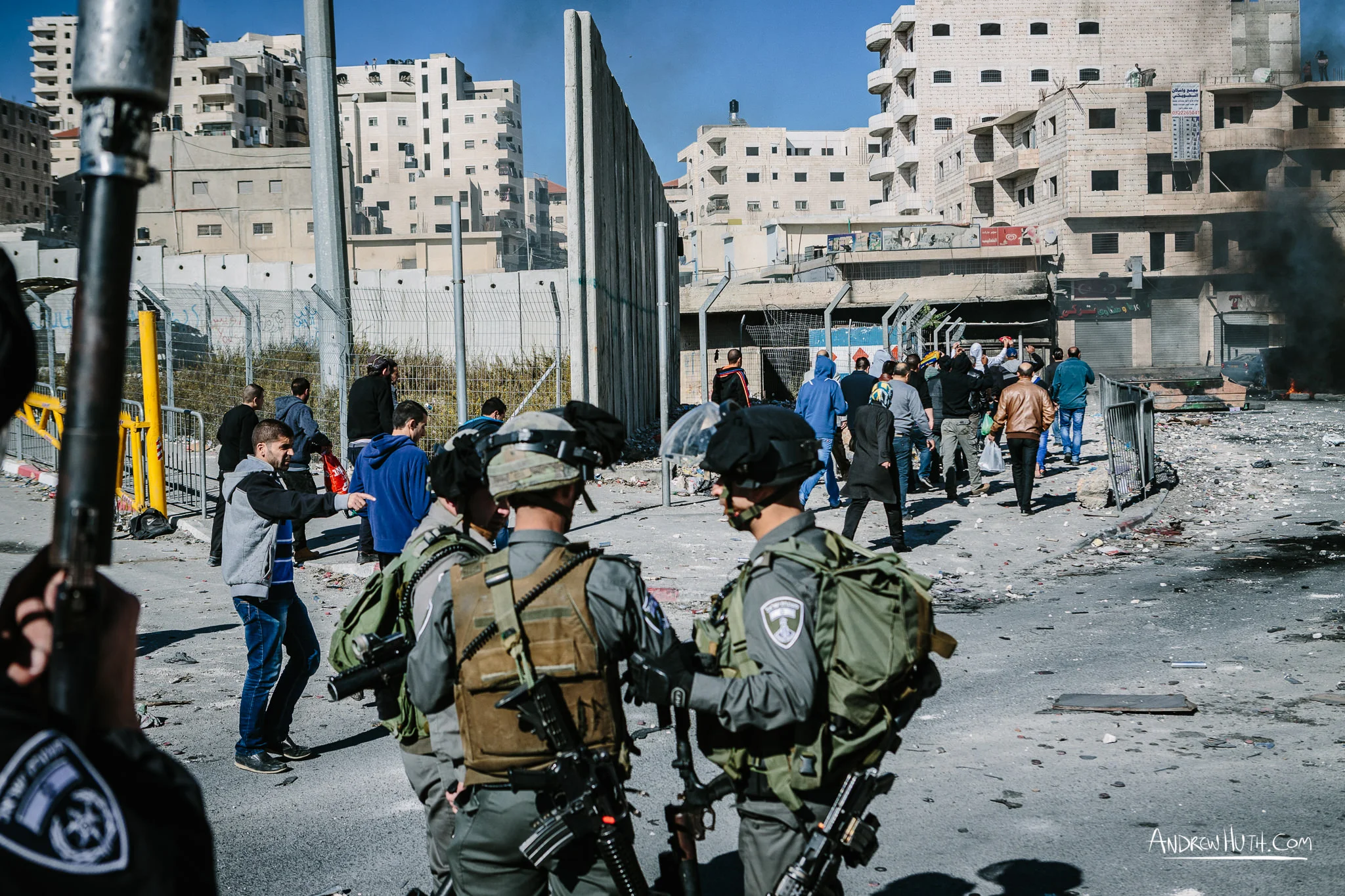 Locals trying to get back in safely after afternoon prayer. They waved toward the refugees to stop tossing rocks because they were coming in. Israeli military using tear gas and guns in an armed conflict with the residents of Shu'afat Refugee Camp. Palestinian youth clash with Israeli military in Shu'afat Refugee Camp in East Jerusalem on Friday, November 7, 2014. The recent, but temporarily total closure of one of Muslim's holiest sites, the Al-Aqsa Mosque, (the first since 1967) and the subsequent limited access for many Muslims to the mosque since has raised tension between Israeli's military and the Arab community.