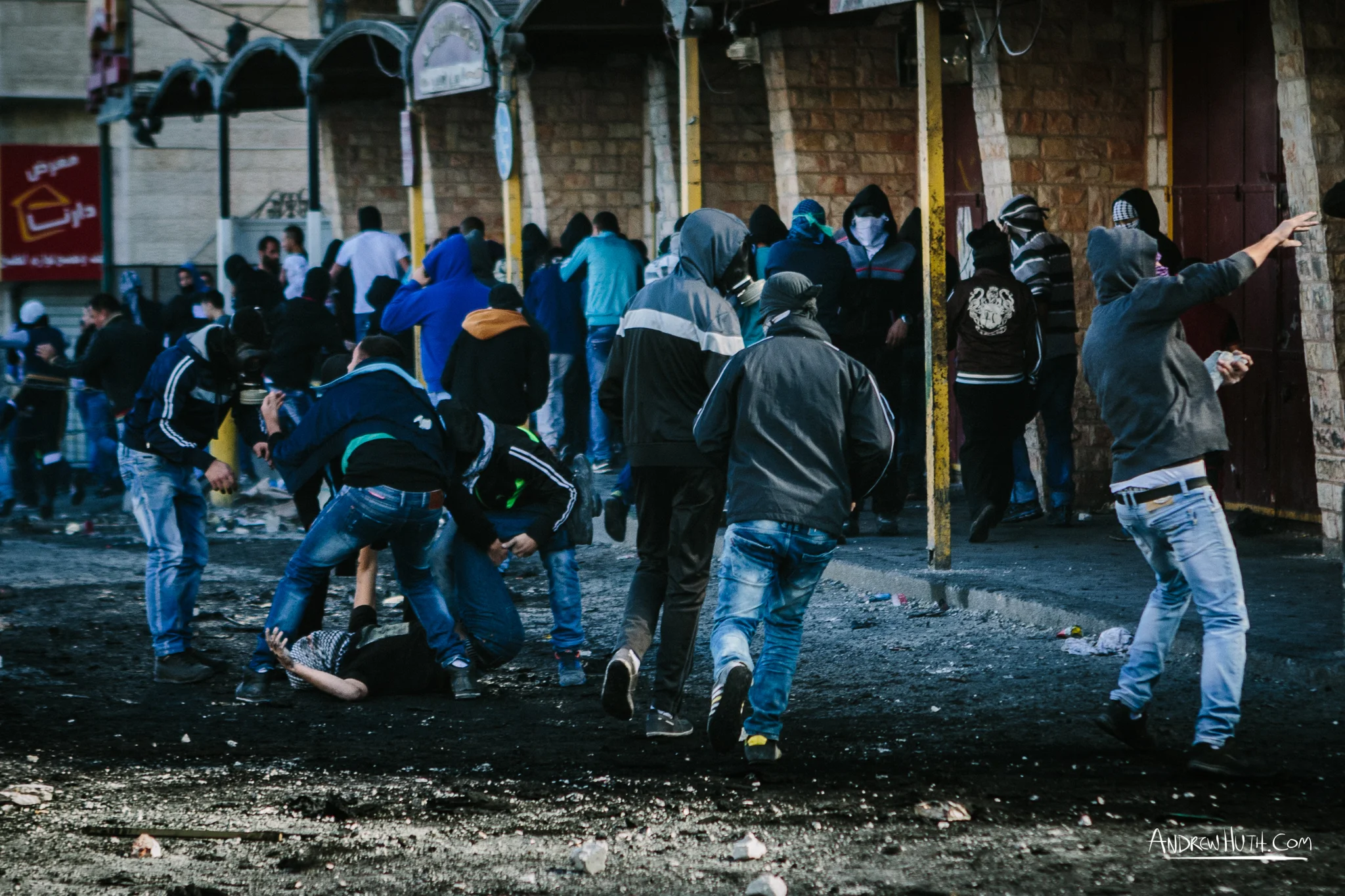 A Palestinian youth who was shot by Israeli military during a clash at Shu'afat Refugee Camp is helped by his friends and quickly carried away. Palestinian youth clash with Israeli military in Shu'afat Refugee Camp in East Jerusalem on Friday, November 7, 2014. The recent, but temporarily total closure of one of Muslim's holiest sites, the Al-Aqsa Mosque, (the first since 1967) and the subsequent limited access for many Muslims to the mosque since has raised tension between Israeli's military and the Arab community.