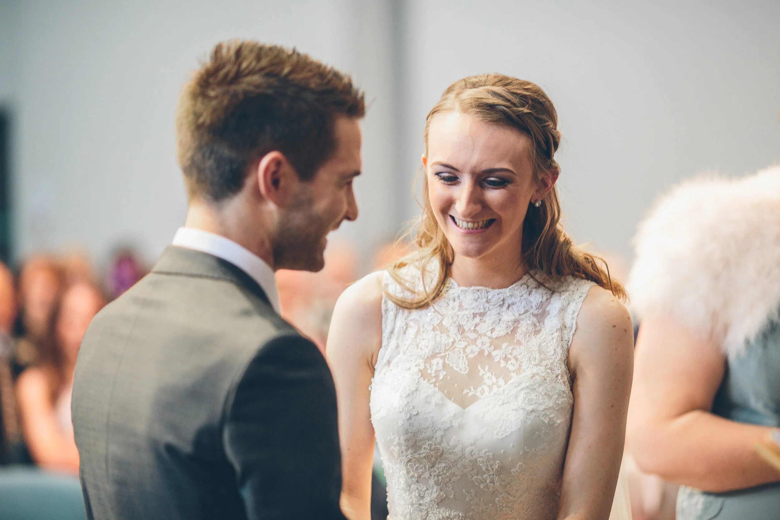 A bride and groom smiling at each other during their wedding ceremony.