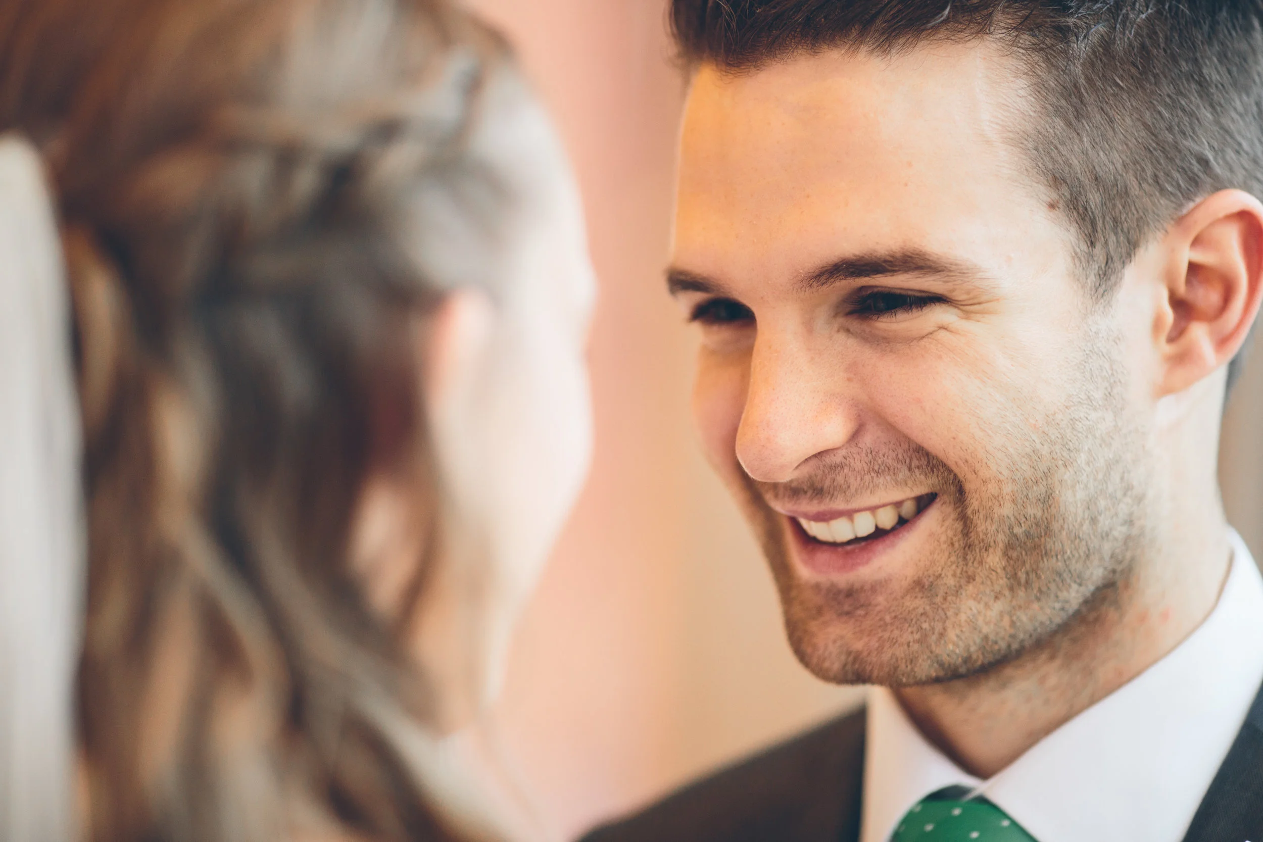 A man smiling warmly at a woman, with a close-up focus on his face, showing happiness and affection.