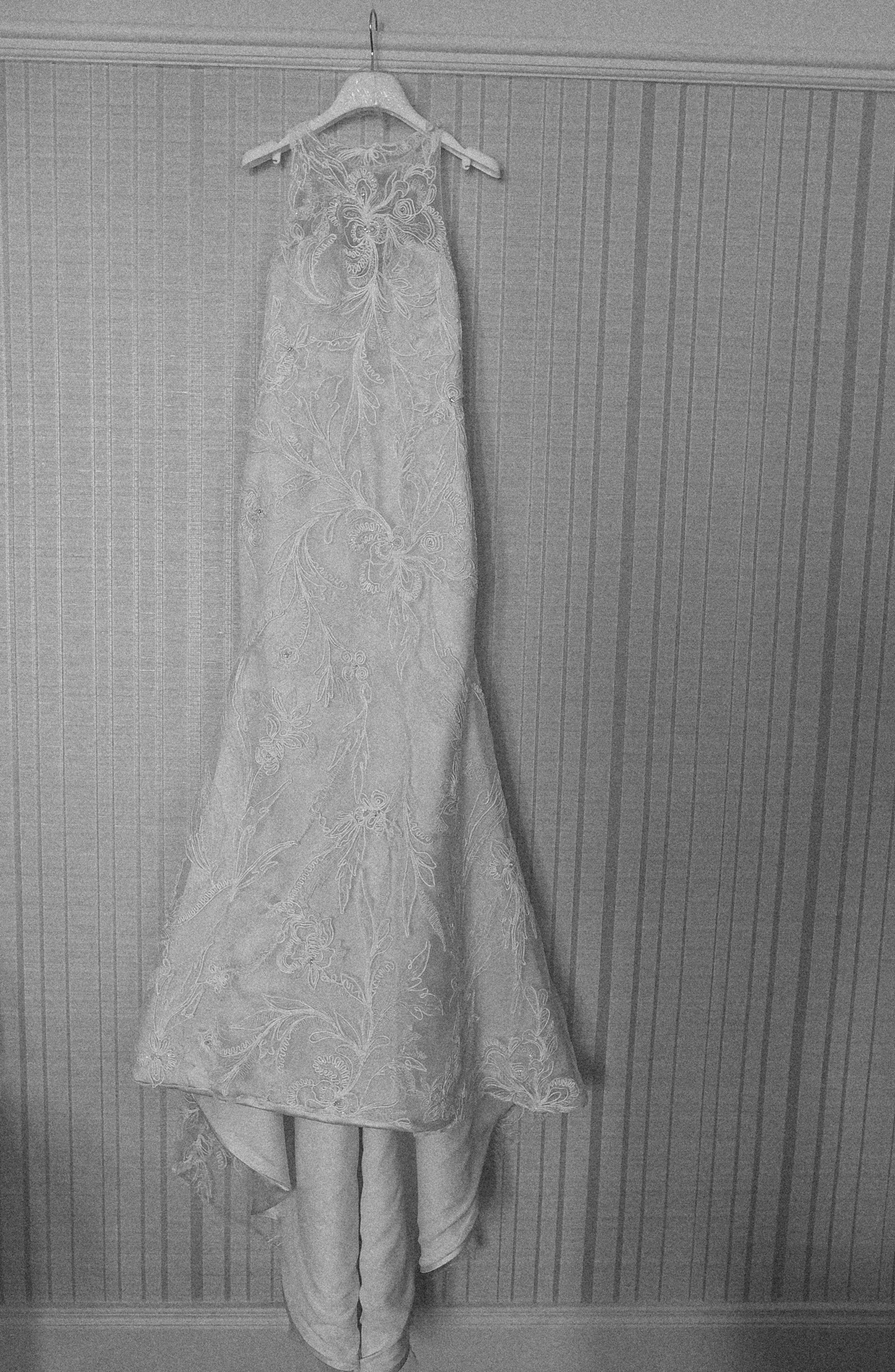 A wedding dress hanging on a wall with patterned wallpaper.