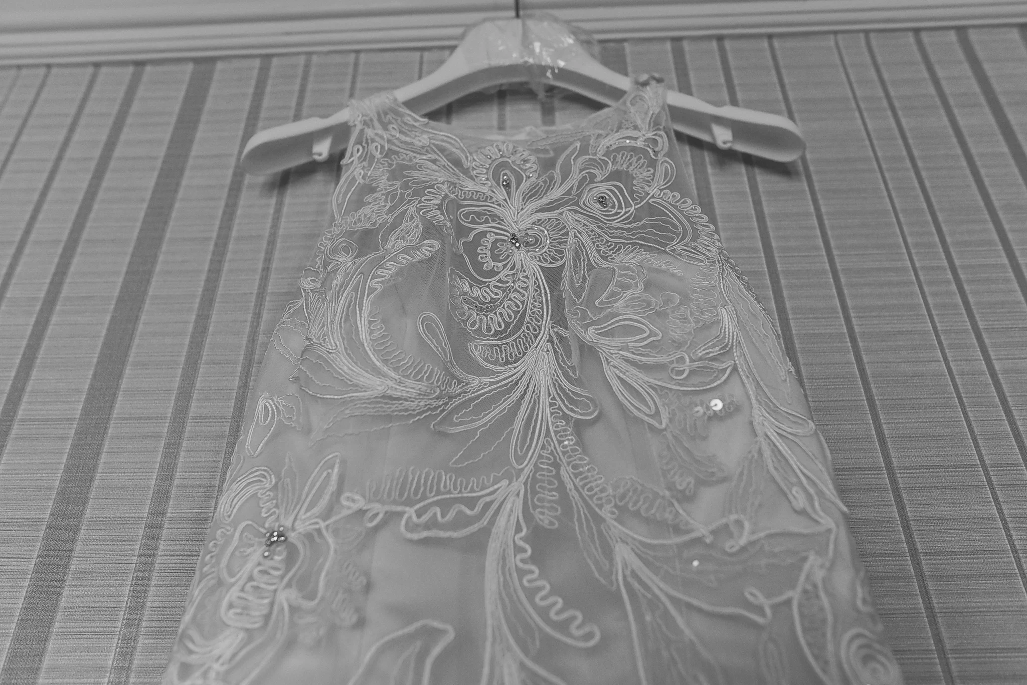 A lace fabric with floral embroidery draped over a hanger.