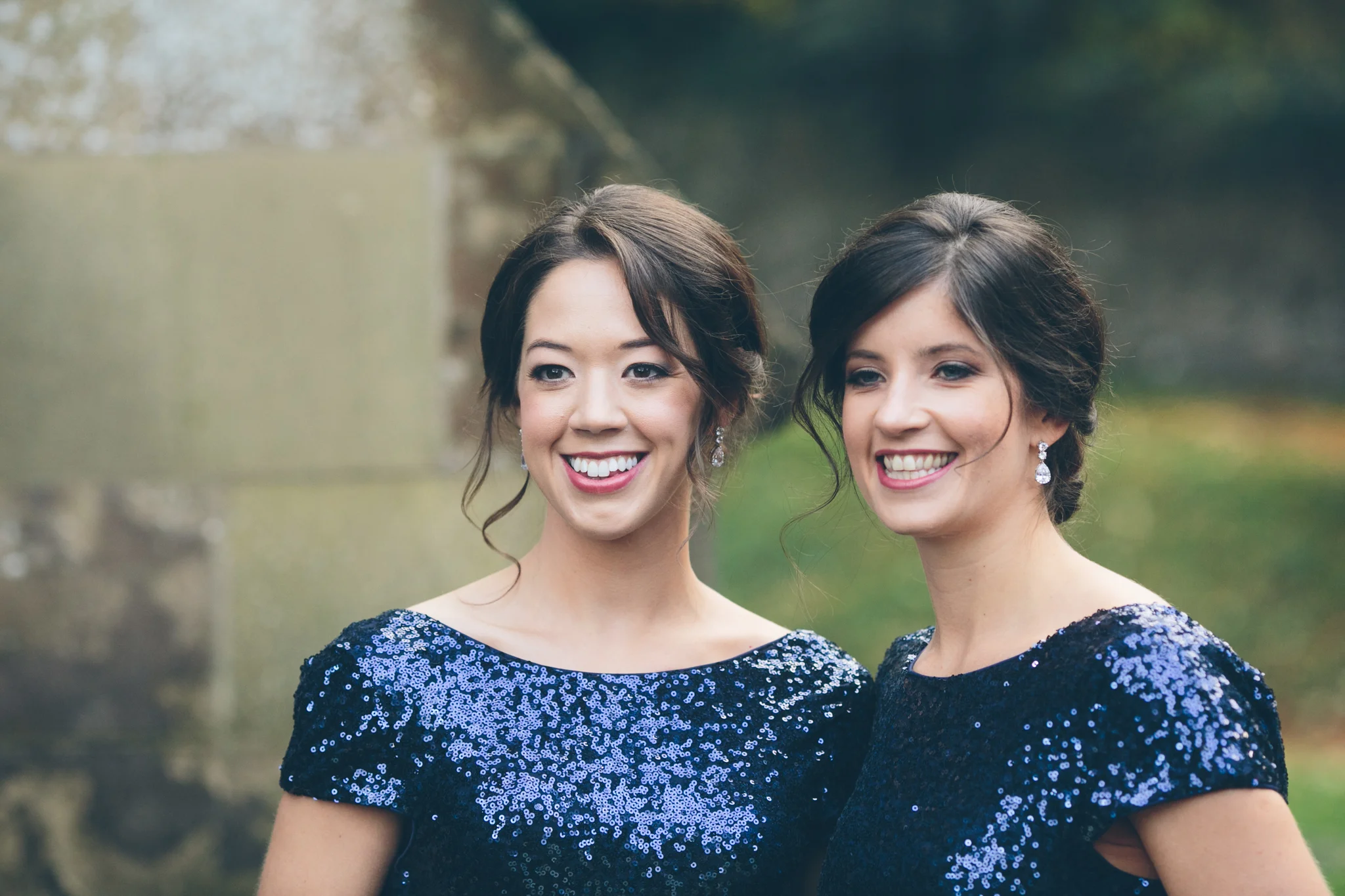 Two women in matching blue sequined dresses smiling outdoors.