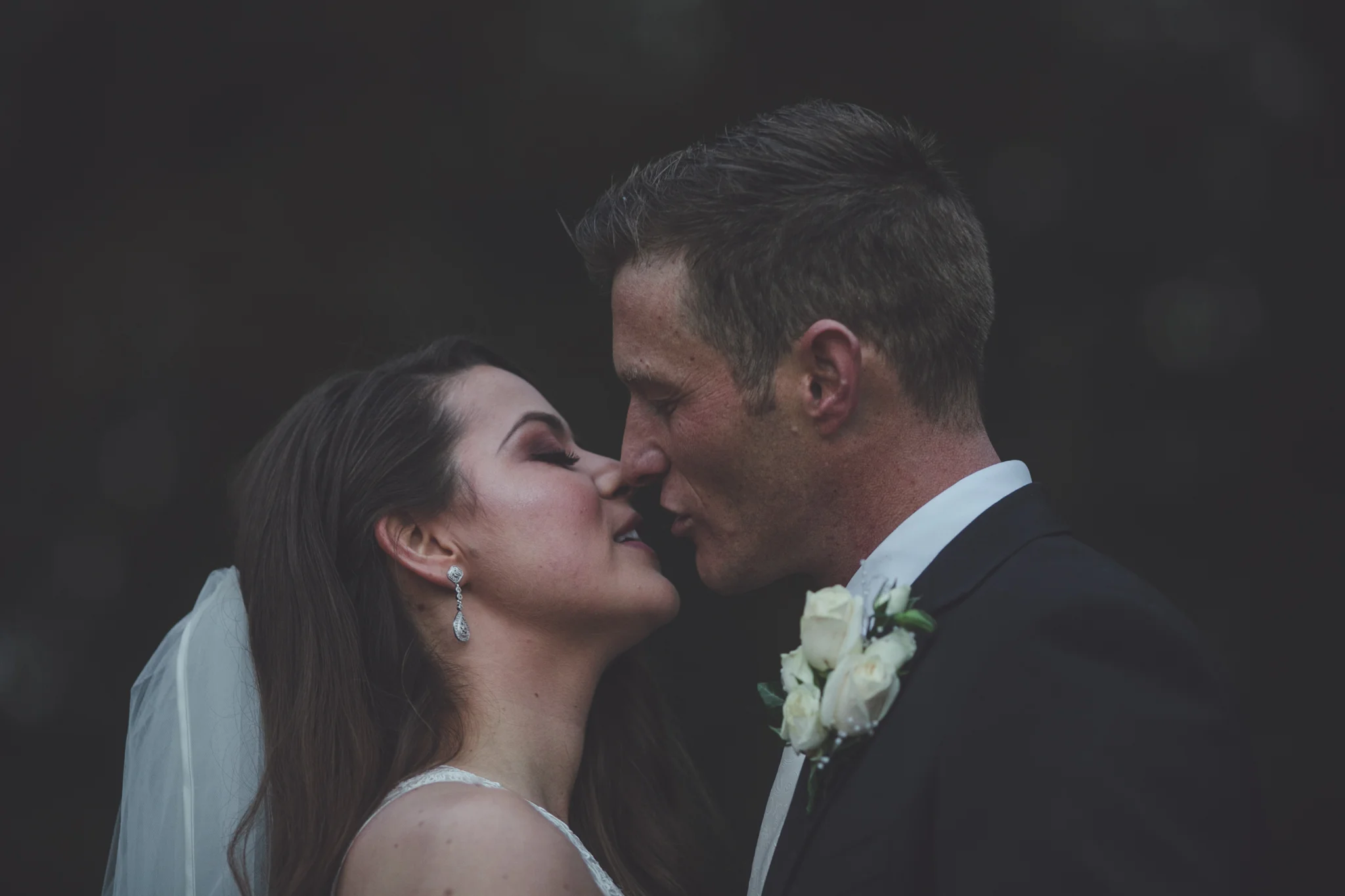 A bride and groom face close together, almost touching noses, during their wedding.